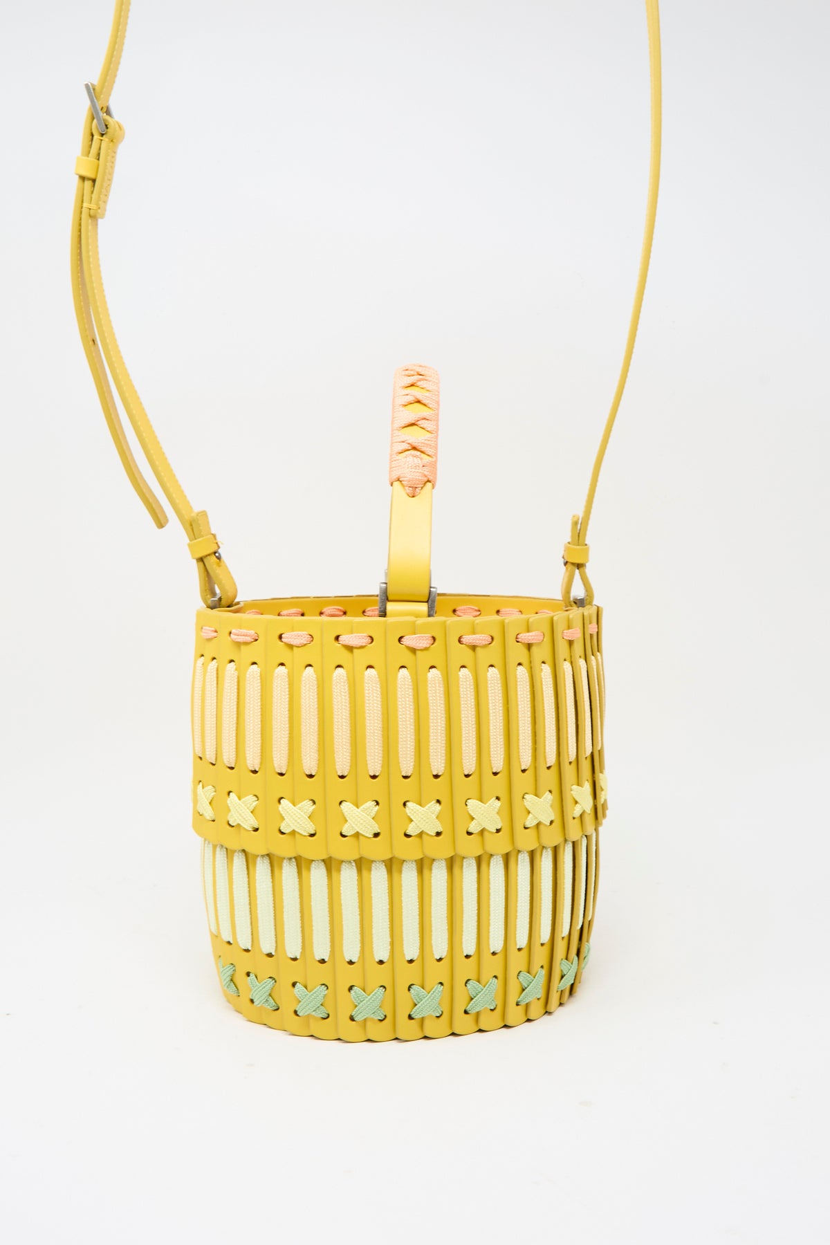 Handcrafted in Japan, this yellow cylindrical Leather Bucket 80 Artist Edition with Holly Coulis features a long shoulder strap and woven cord detailing in pink, white, and green.