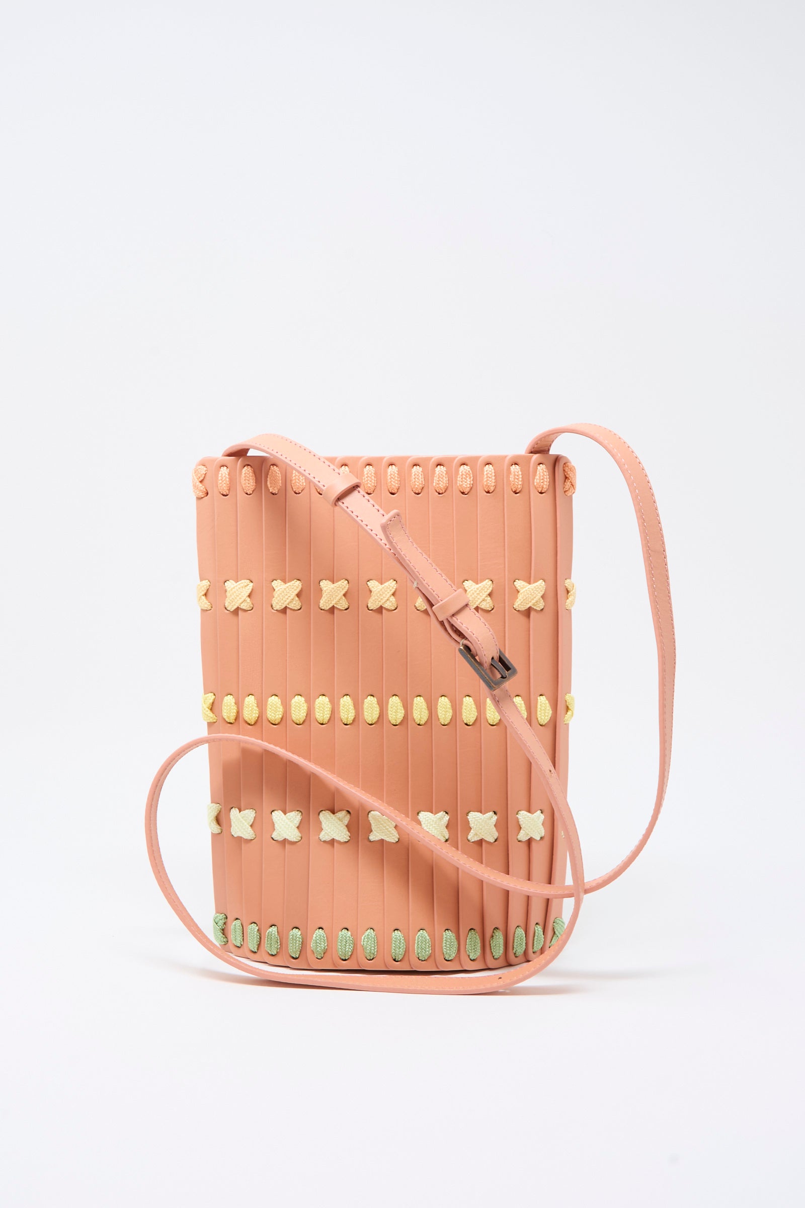 Introducing the Hatori Leather Crossbody 30 in Pink with Multi Lacing—a small handcrafted bag featuring vertical ridges and decorative yellow and green stitching, showcased against a plain white background.