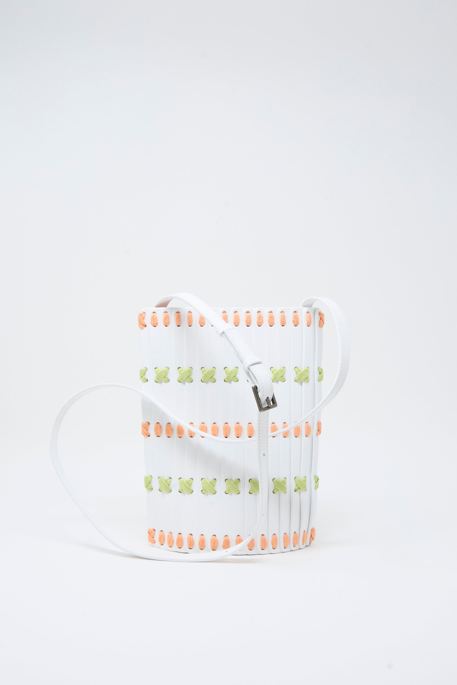 A handcrafted rectangular white Leather Crossbody 30 by Hatori, featuring multi-color lacing in orange and green accents, detailed with vertical slats and a long white strap, set against a plain white background.