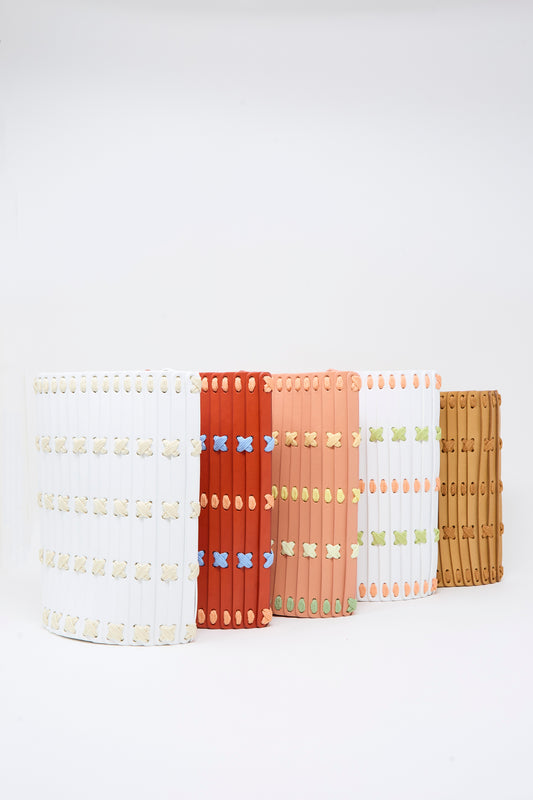 Five Leather Crossbody 30 bags in White with Multi Lacing by Hatori are arranged in a row against a white background, showcasing the artistry of handcrafted design.