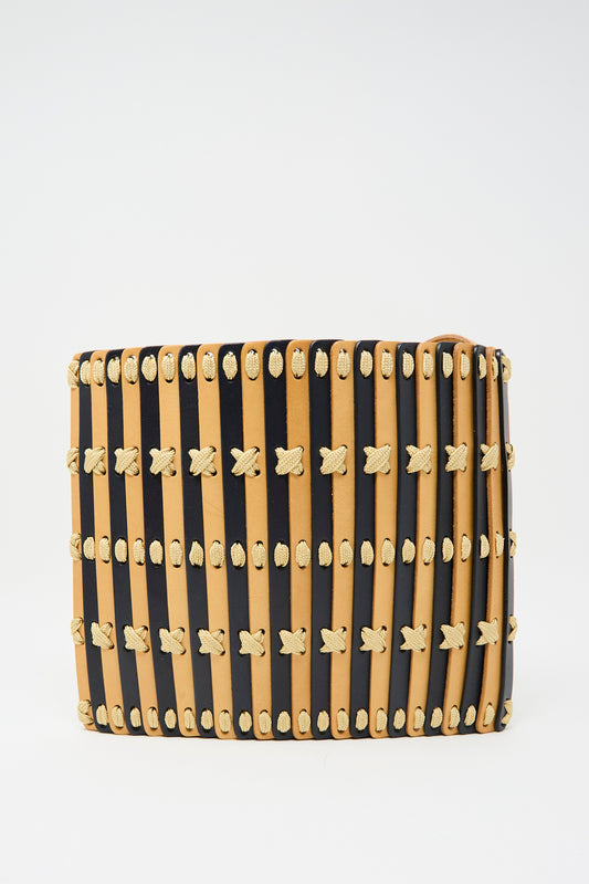 Hatori’s Leather Crossbody 48 features alternating vertical strips of midnight blue leather, ecru lace accents with X-shaped stitching, and an adjustable shoulder strap.