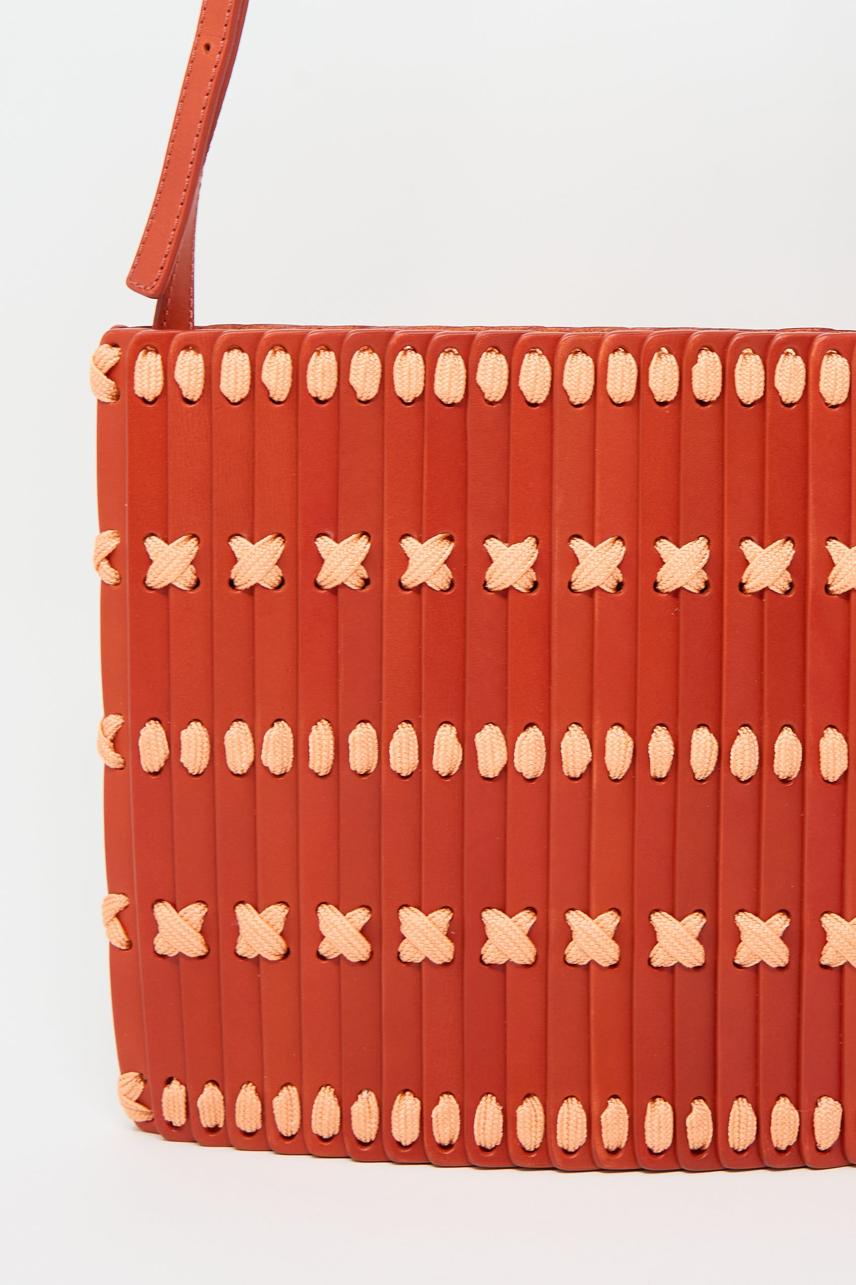 Close-up of a Hatori Leather Crossbody in Red with Light Coral Lace, featuring an adjustable shoulder strap, against a plain white background.