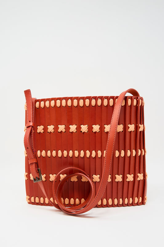 The Hatori Leather Crossbody 48 Bag in Tomato with Pink Lace features a rectangular woven design, adjustable shoulder strap, red leather and beige details, and a minimalist aesthetic.