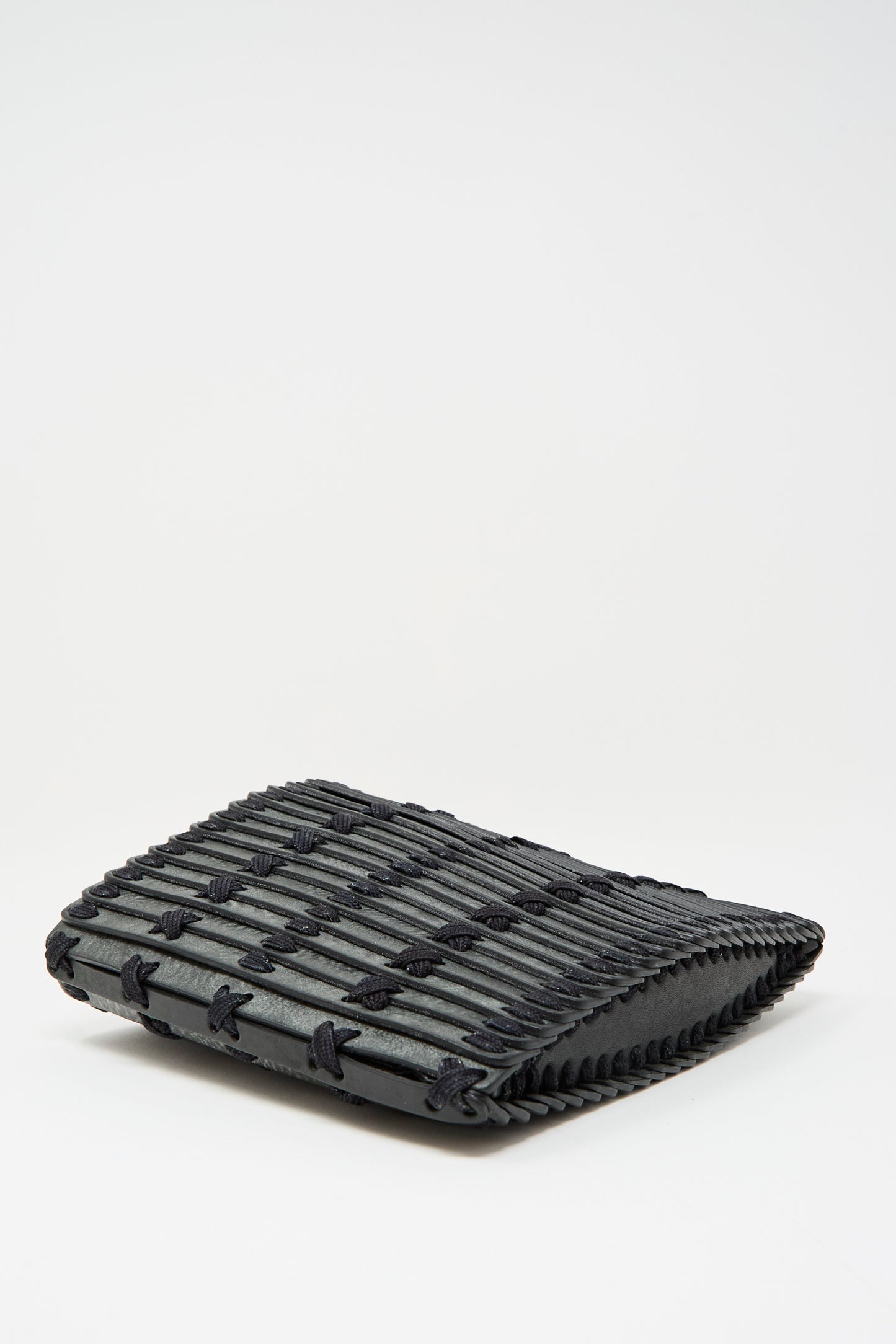 The Hatori Leather Crossbody 48 Bag in Waxed Coated Black with Indigo Lace features a rectangular silhouette, grid-like textured finish, and adjustable shoulder strap, shown against a plain white background.