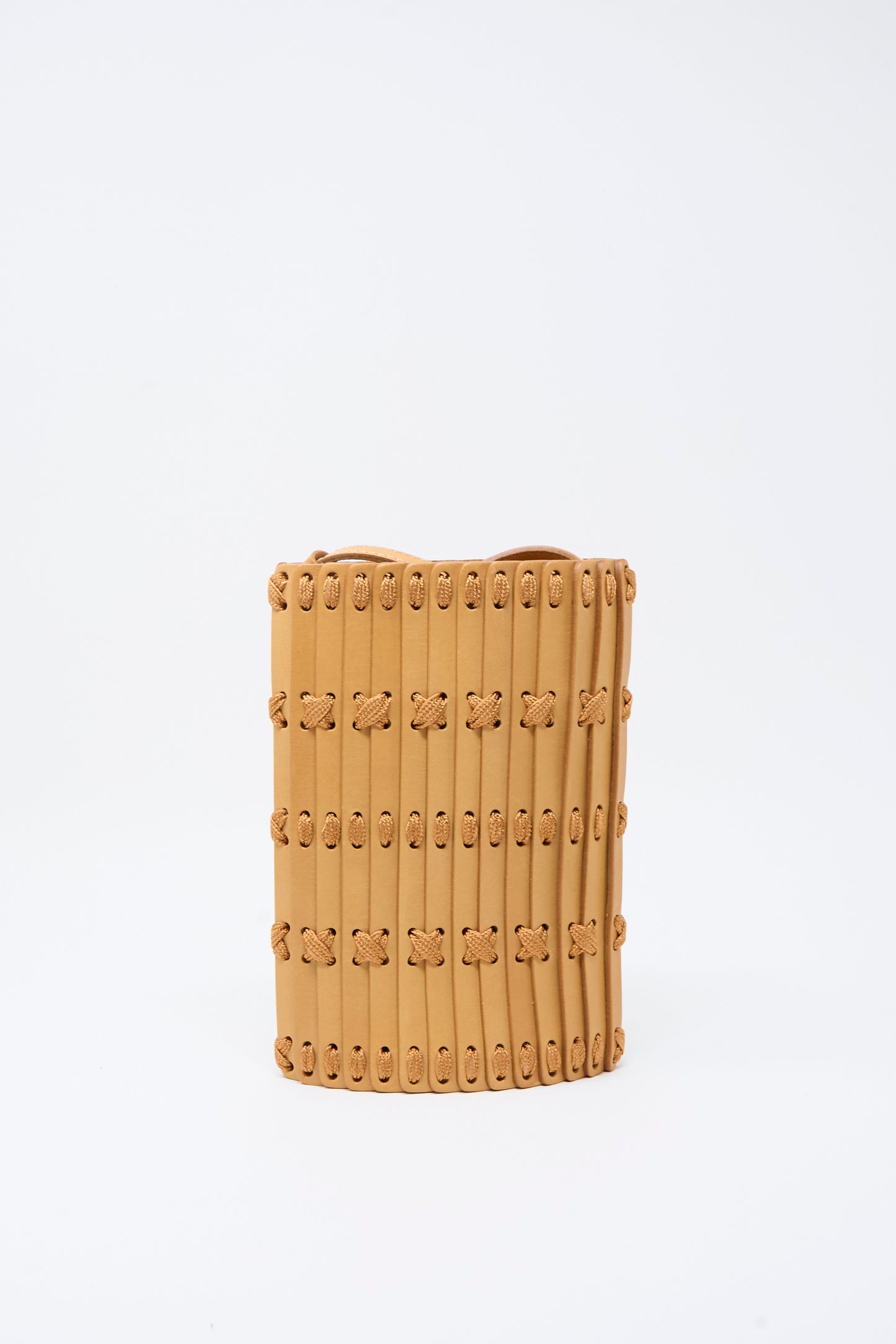 Hatori’s Leather Phone 26 Bag in Natural with Tan Lacing is a cylindrical shoulder bag, handcrafted from vegetable-tanned leather featuring a vertical panel design and interwoven knots, displayed against a plain white background.