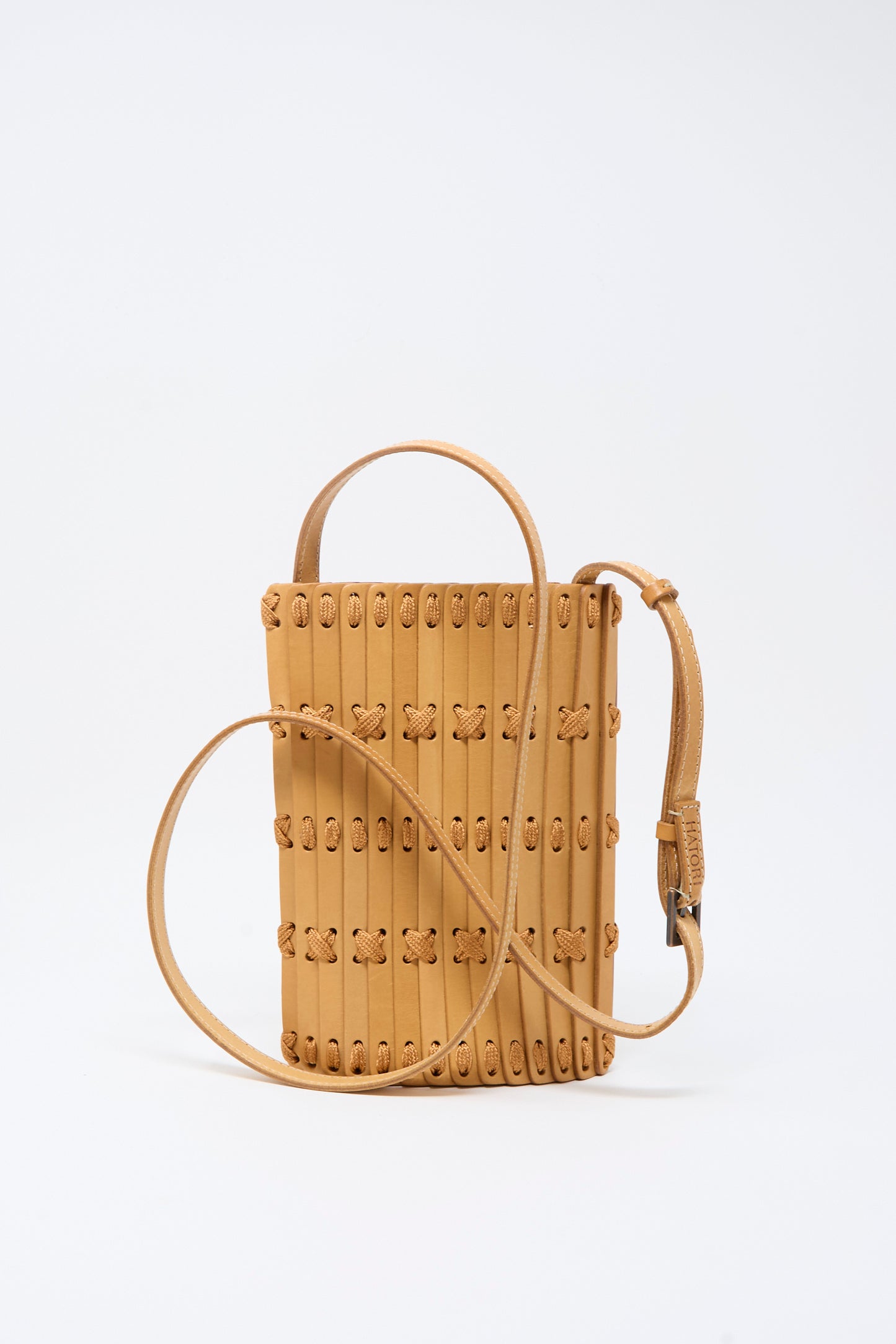 The Hatori Leather Phone 26 Bag in Natural with Tan Lacing is a handcrafted rectangular crossbody featuring vertical stitching, looped lacing accents, a top handle, and an adjustable shoulder strap—expertly made from premium vegetable-tanned leather and shown against a plain white background.