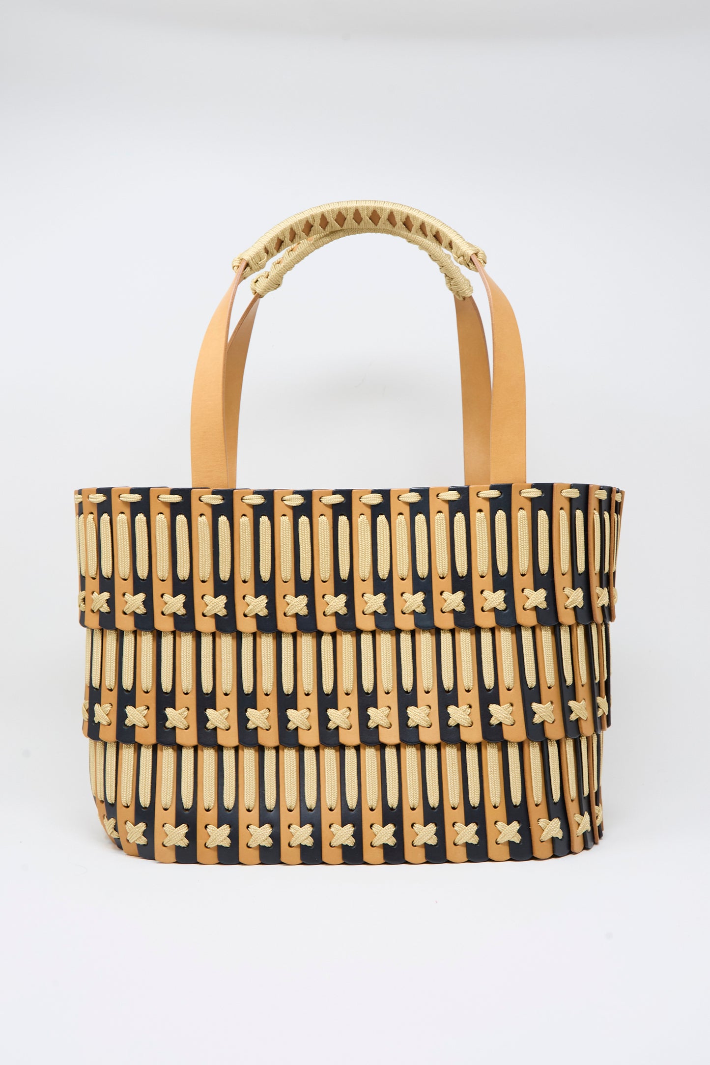 The Hatori Leather Tote 198 in Bi-Color with Tan Lacing features tan handles and layered black, beige, and tan patterned bands. Handcrafted in Tokyo, it is displayed against a plain white background.