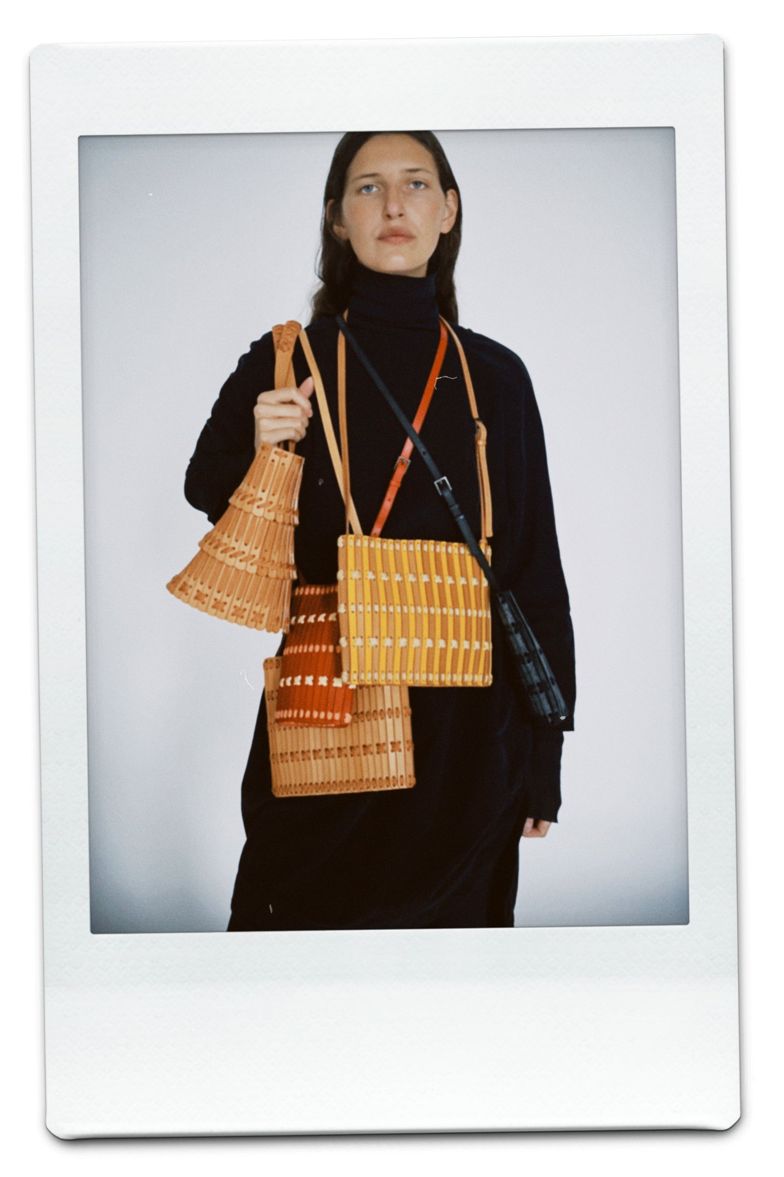 Person holding three woven bags against a plain background