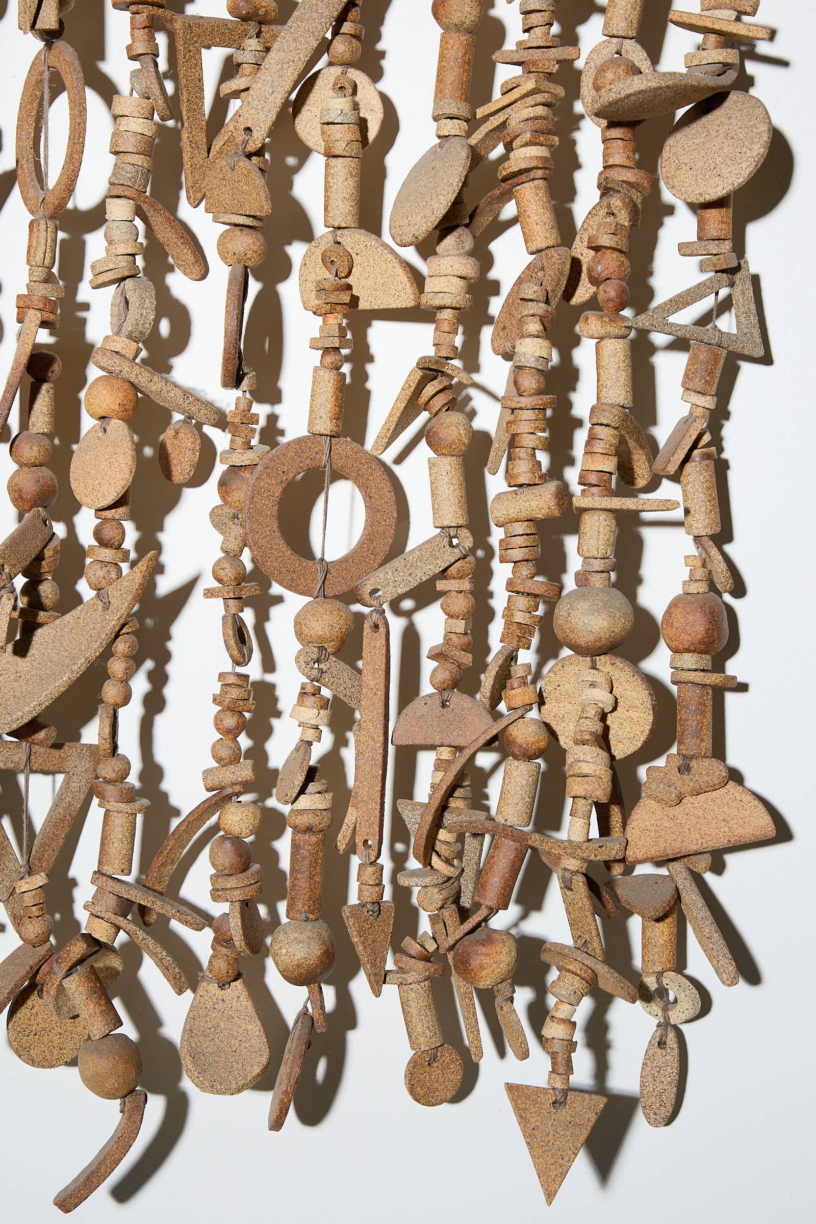 A close-up of the XL Wall Hanging in Natural by Heather Levine, a handmade art installation featuring an array of small, rusted metal pieces in various shapes and sizes, all intricately connected by string or wire. Available for in-store pickup.