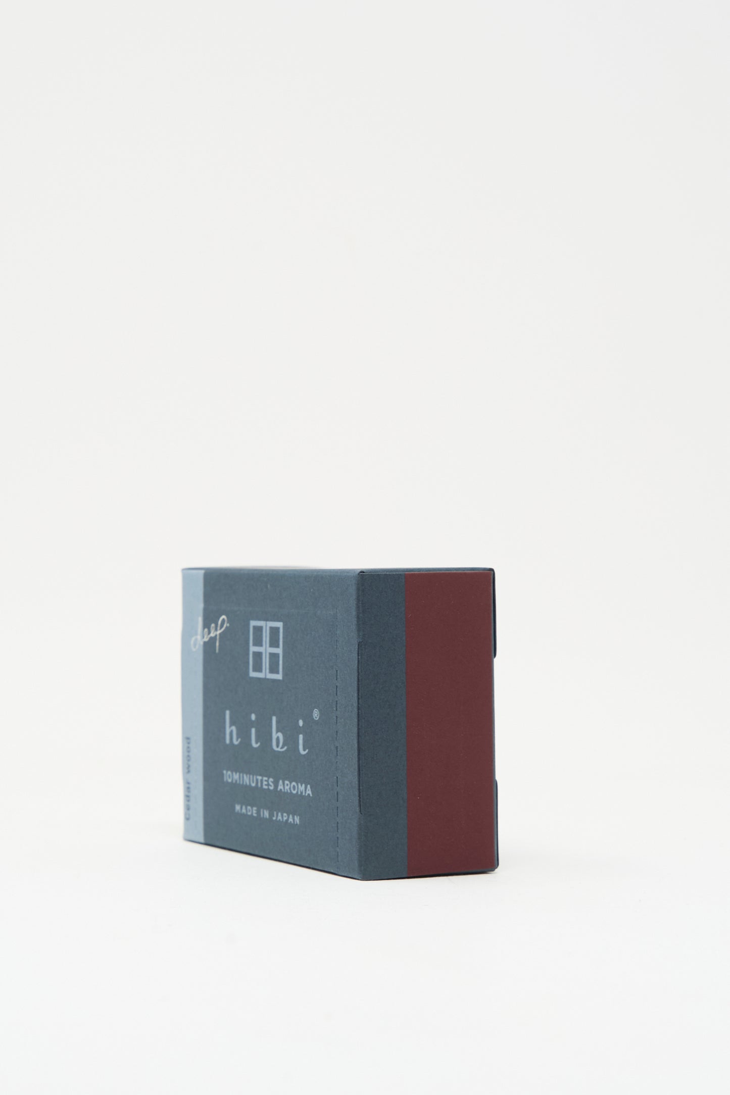 A rectangular blue and maroon box labeled "Hibi Cedarwood Incense Matches" rests on a white background, containing Japanese incense matches that provide a calming cedar aroma.