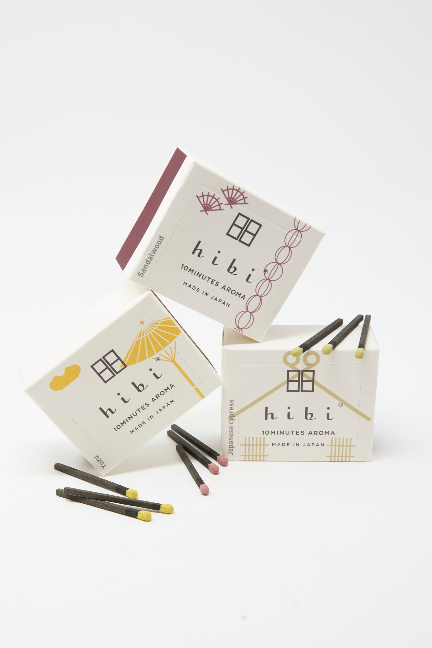 Three boxes of Hibi Incense Matches, featuring minimalist design, are displayed with several handcrafted matches in front.
