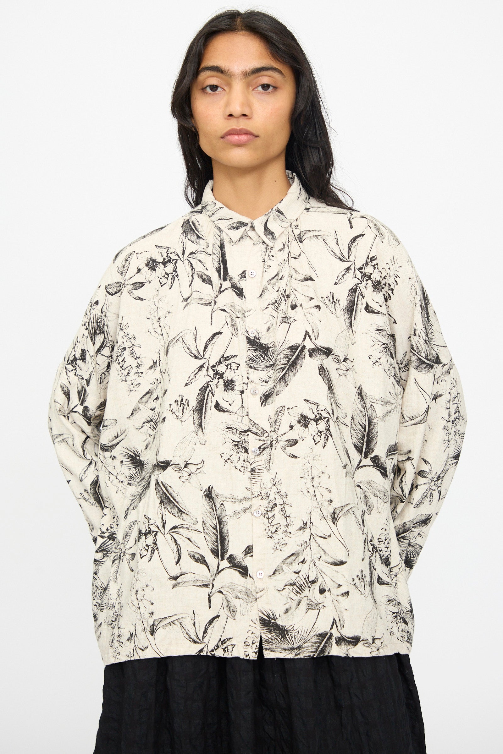 Model wears the Ichi Antiquités Botanical Print Shirt in Natural, featuring a relaxed fit and long sleeves with a black and beige botanical pattern, paired with a black skirt against a plain light background.