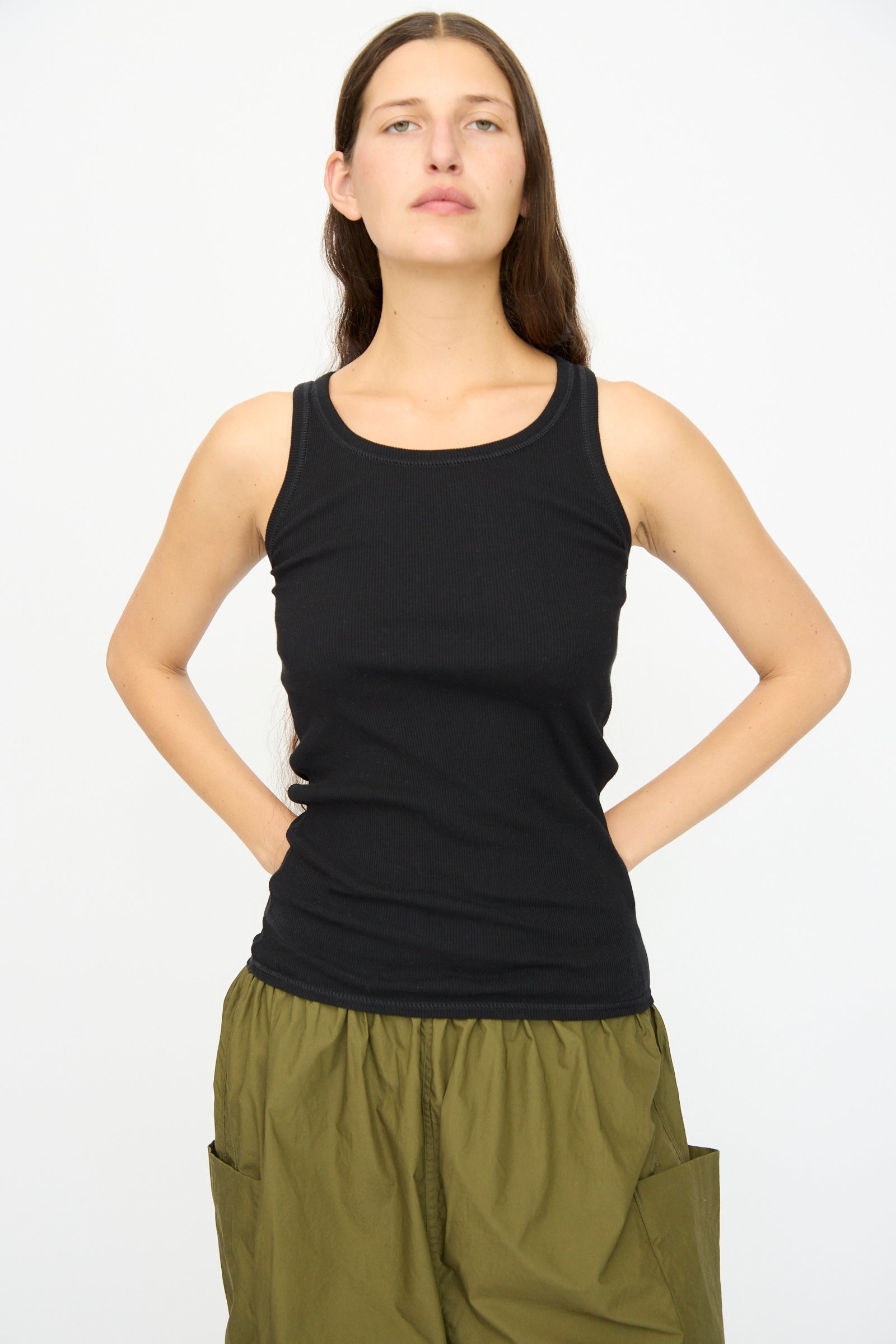 A person faces forward against a plain white background, wearing the Ichi Antiquités Cotton Cashmere Tank Top in Black and olive green pocket pants.