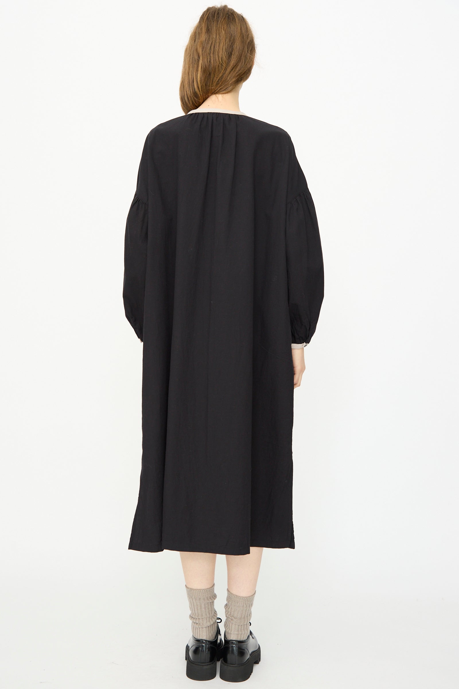 Person shown from the back against a white background, wearing the Ichi Antiquités Cotton Cashmere Viyella Dress in Black, paired with gray socks and black shoes.
