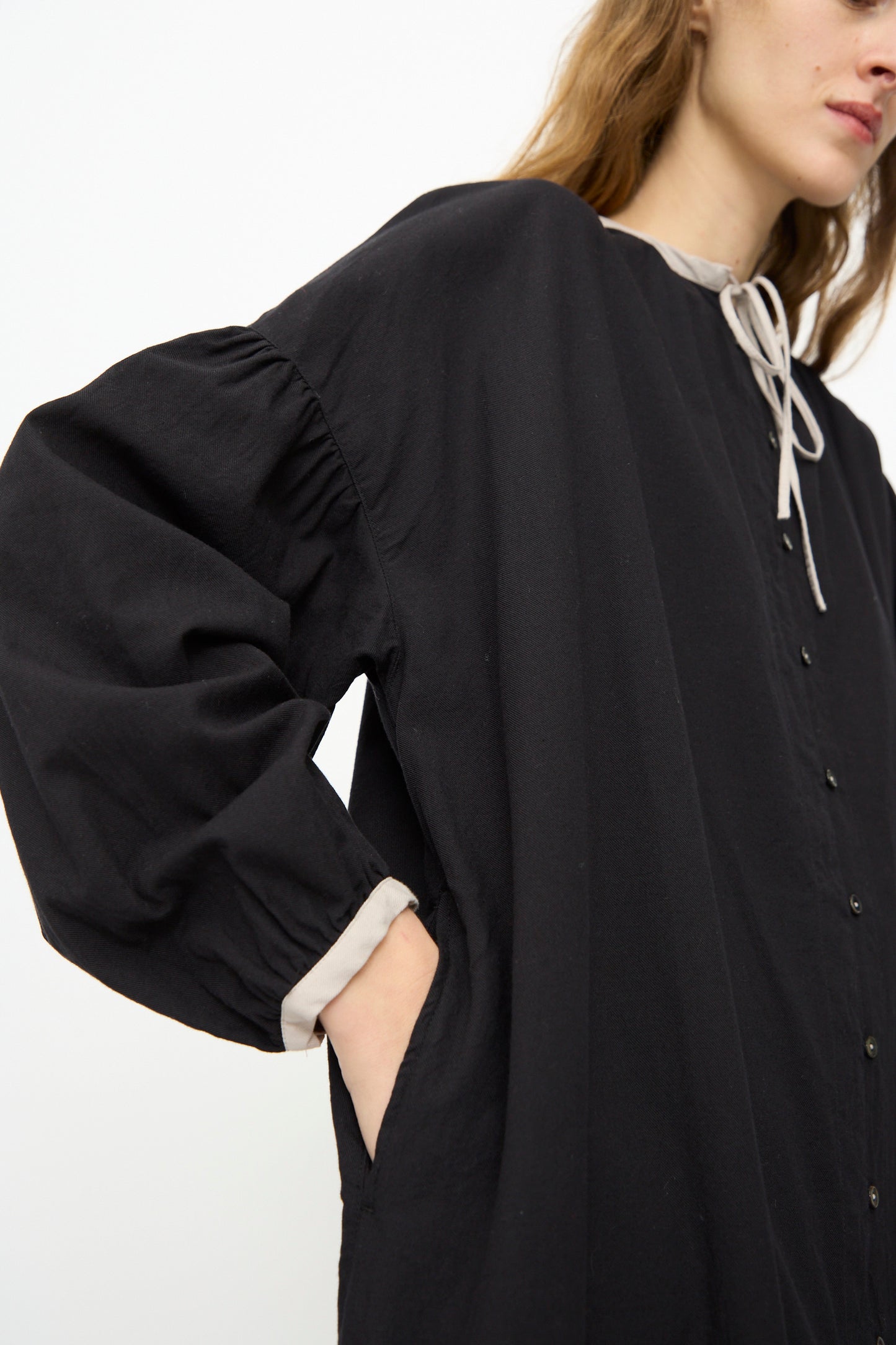 Shown from the shoulders down, a person wears the Ichi Antiquités Cotton Cashmere Viyella Dress in Black, featuring light-colored trim and a pocket.