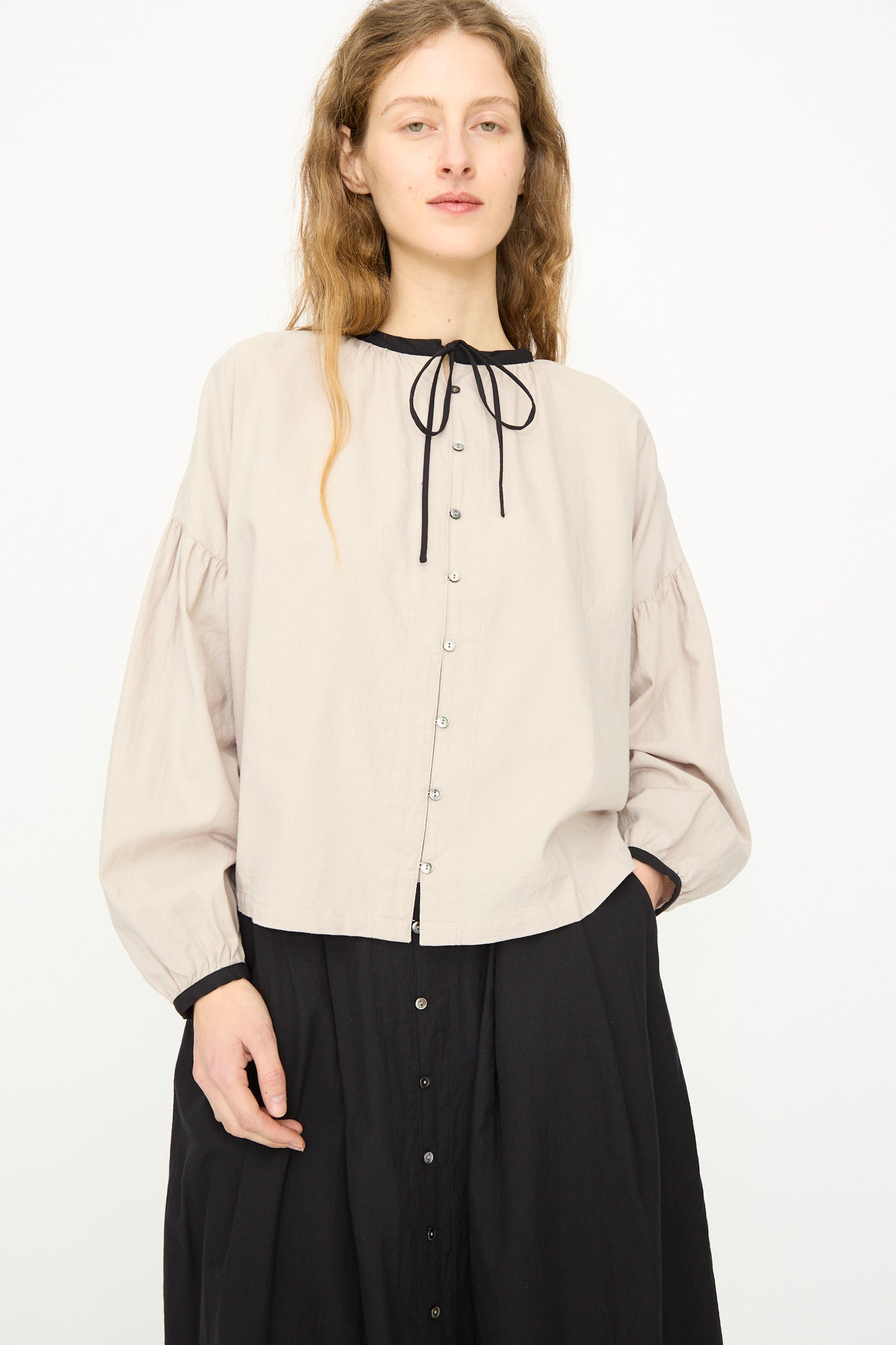 A woman in the Ichi Antiquités Cotton Cashmere Viyella Shirt in Natural, featuring a black necktie and black skirt, stands against a plain white background.