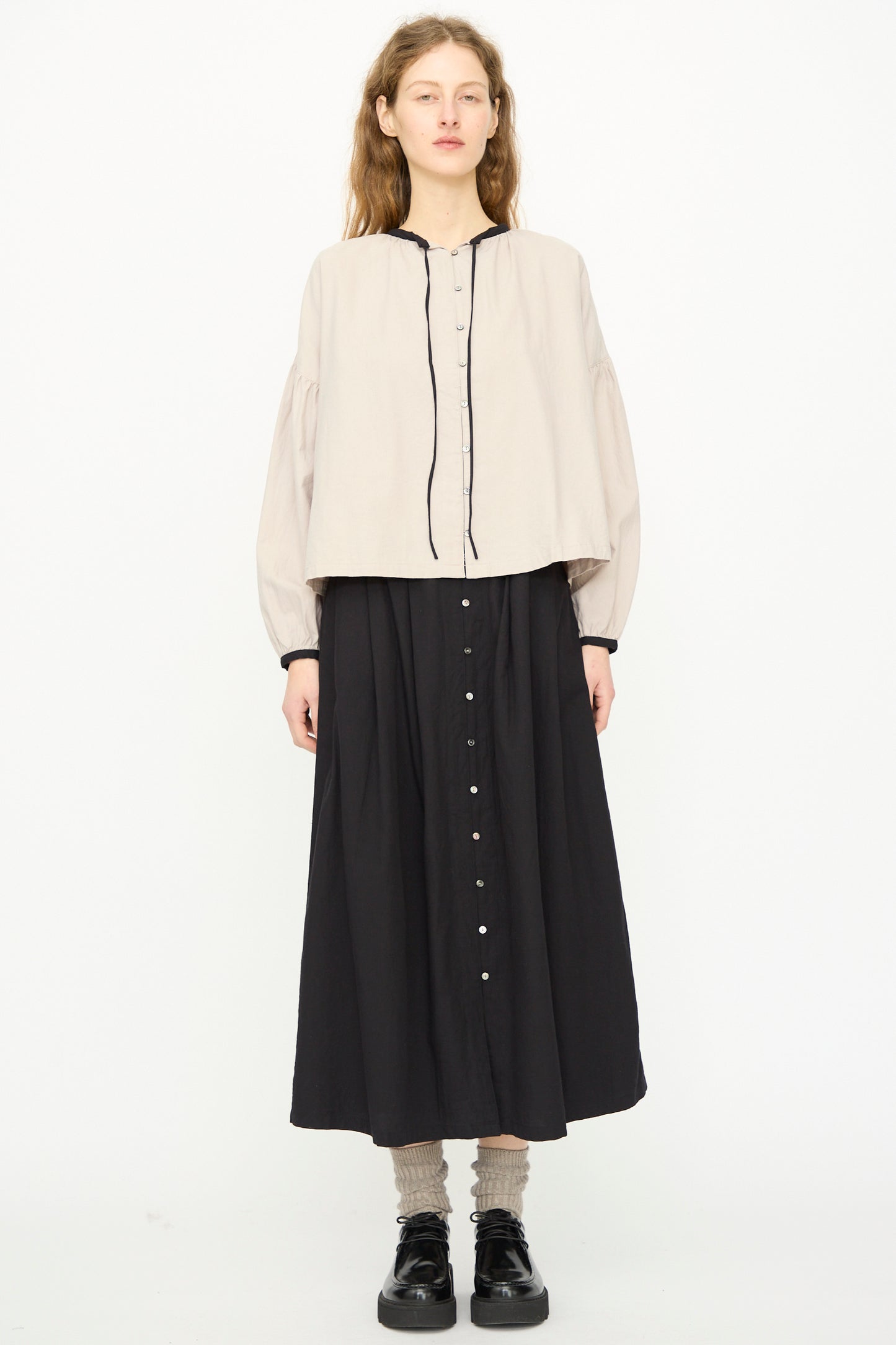 A woman faces forward wearing the Ichi Antiquités Cotton Cashmere Viyella Shirt in Natural, styled with a long black skirt and black shoes against a plain white background. 