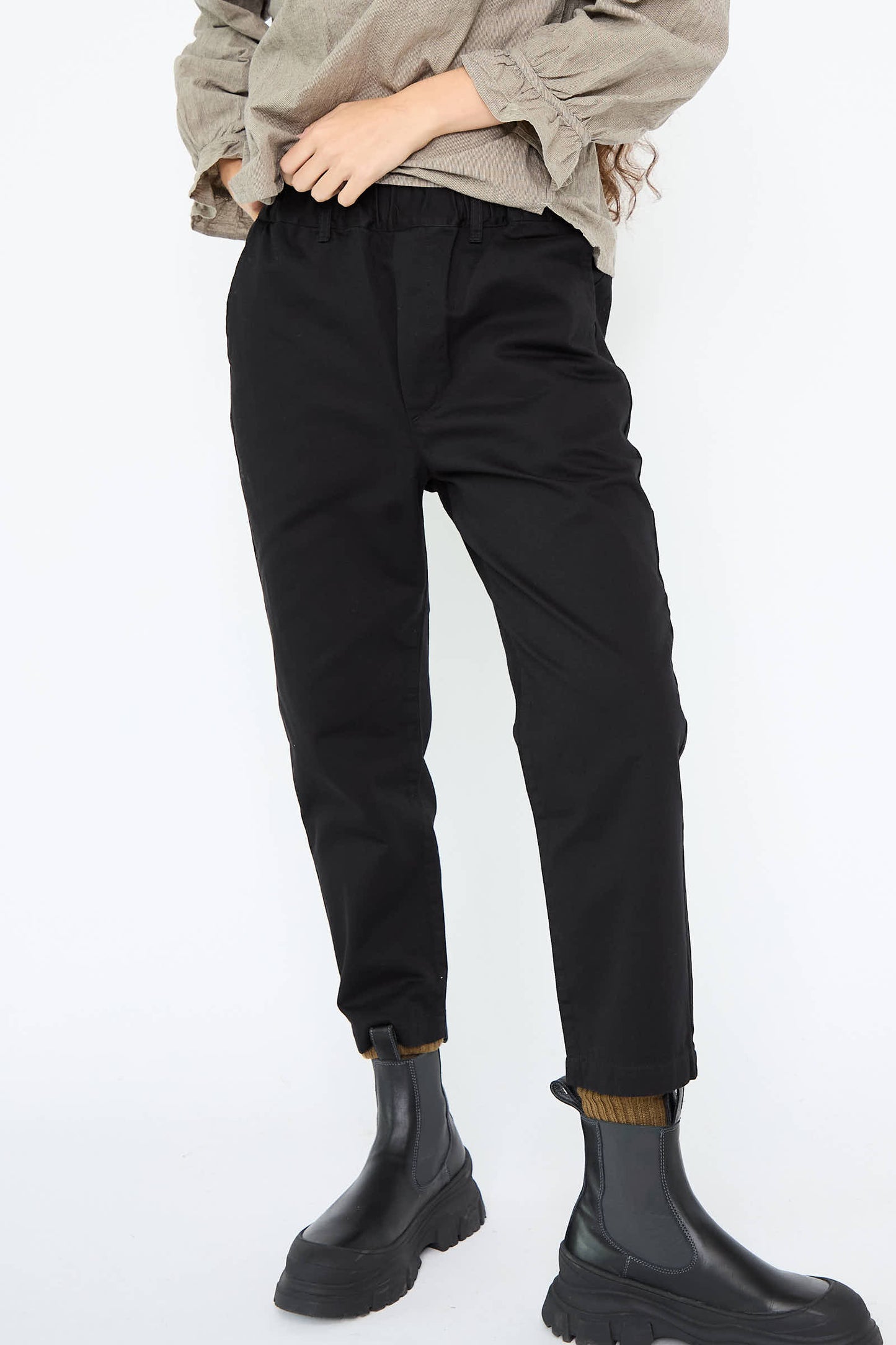 A person wearing the Cotton Cropped Sarrouel Pant in Black by Ichi Antiquités, paired with a beige top and black boots, stands against a plain white background.