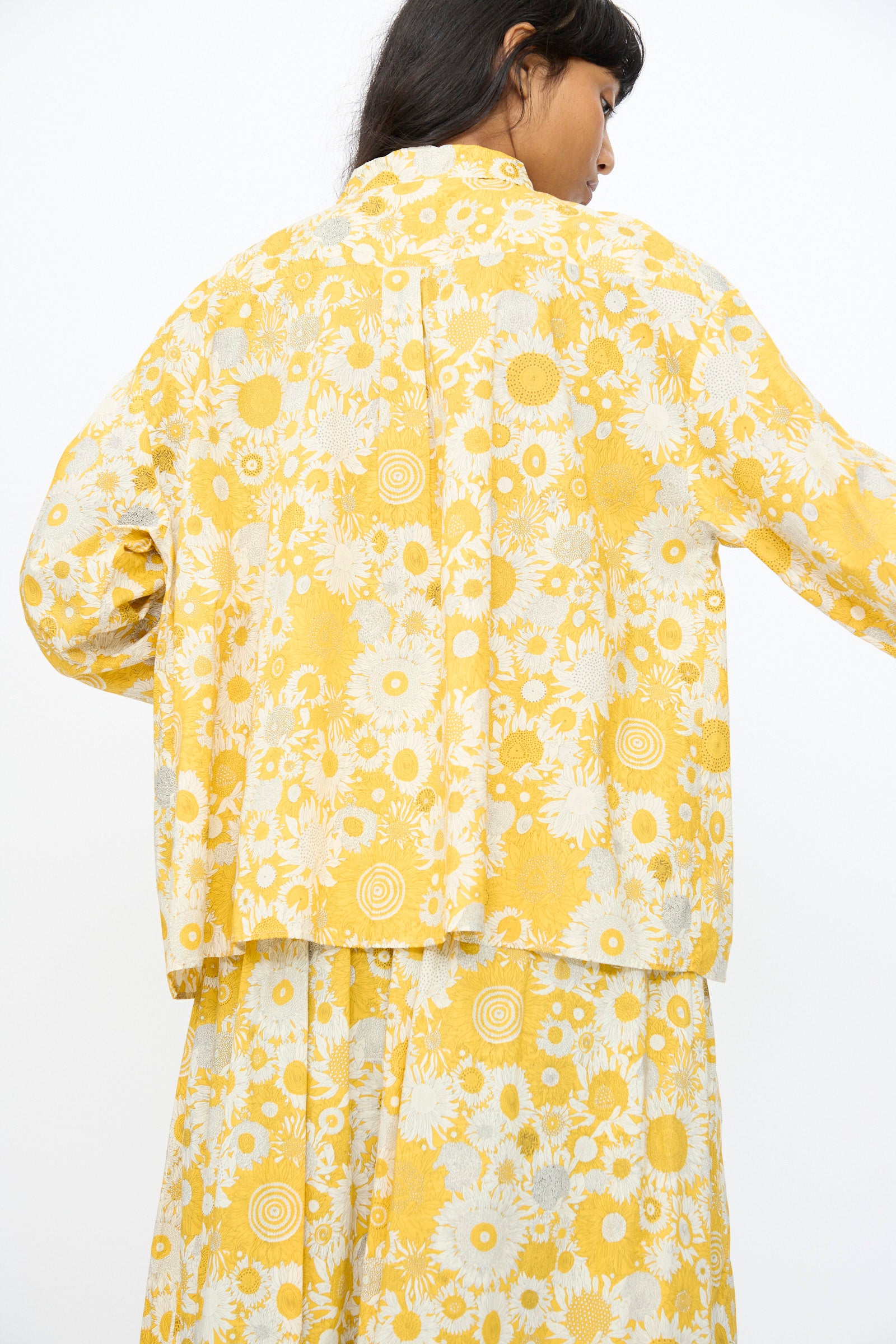 Photographed from the back against a plain white background, the model wears the Ichi Antiquités Cotton Liberty Shirt in Yellow, styled with a matching yellow and white floral-patterned jacket and skirt.