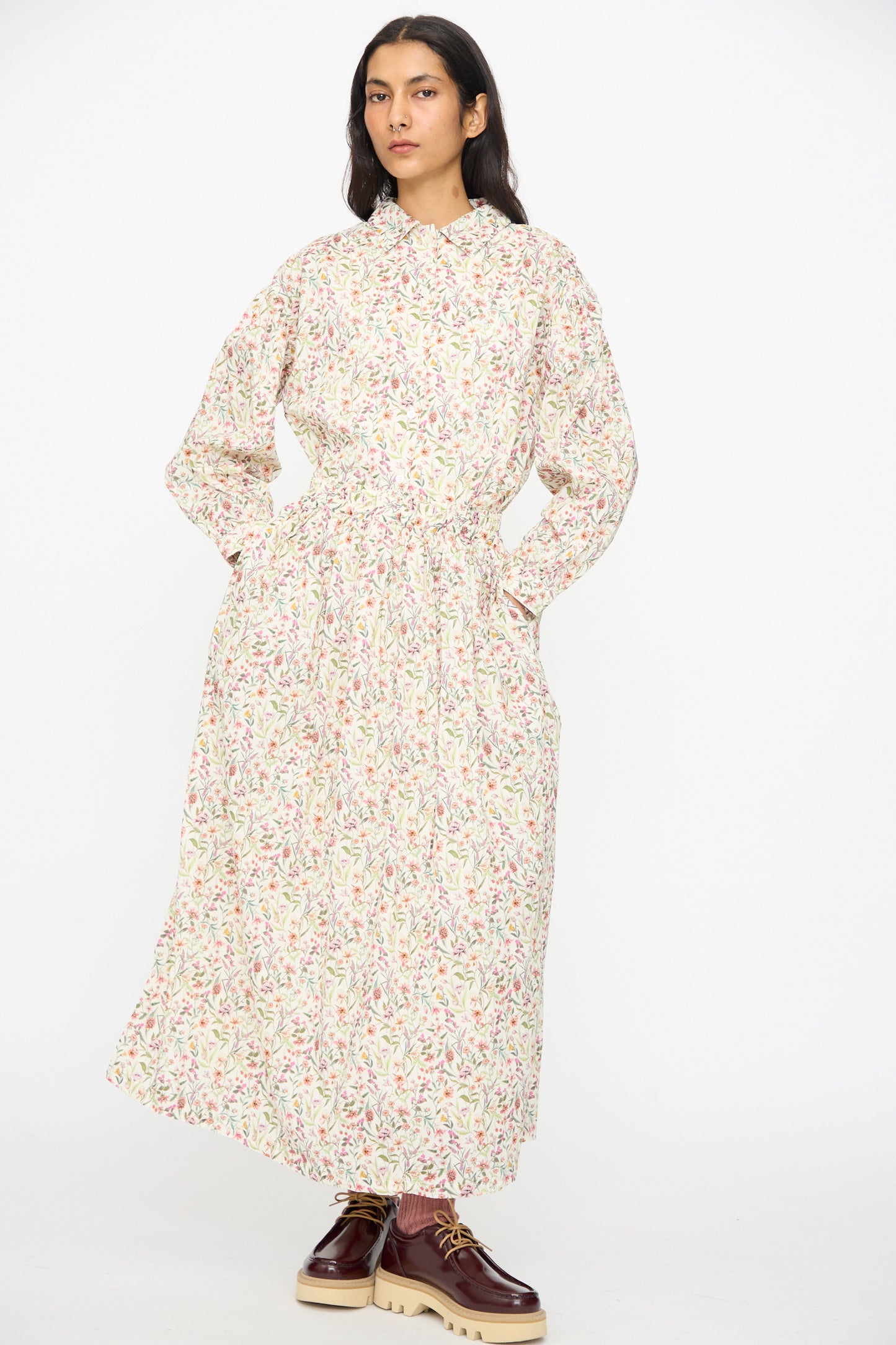 A person stands facing forward in an Ichi Antiquités Cotton Liberty Skirt in Flower Print, paired with burgundy platform shoes, against a plain white background.
