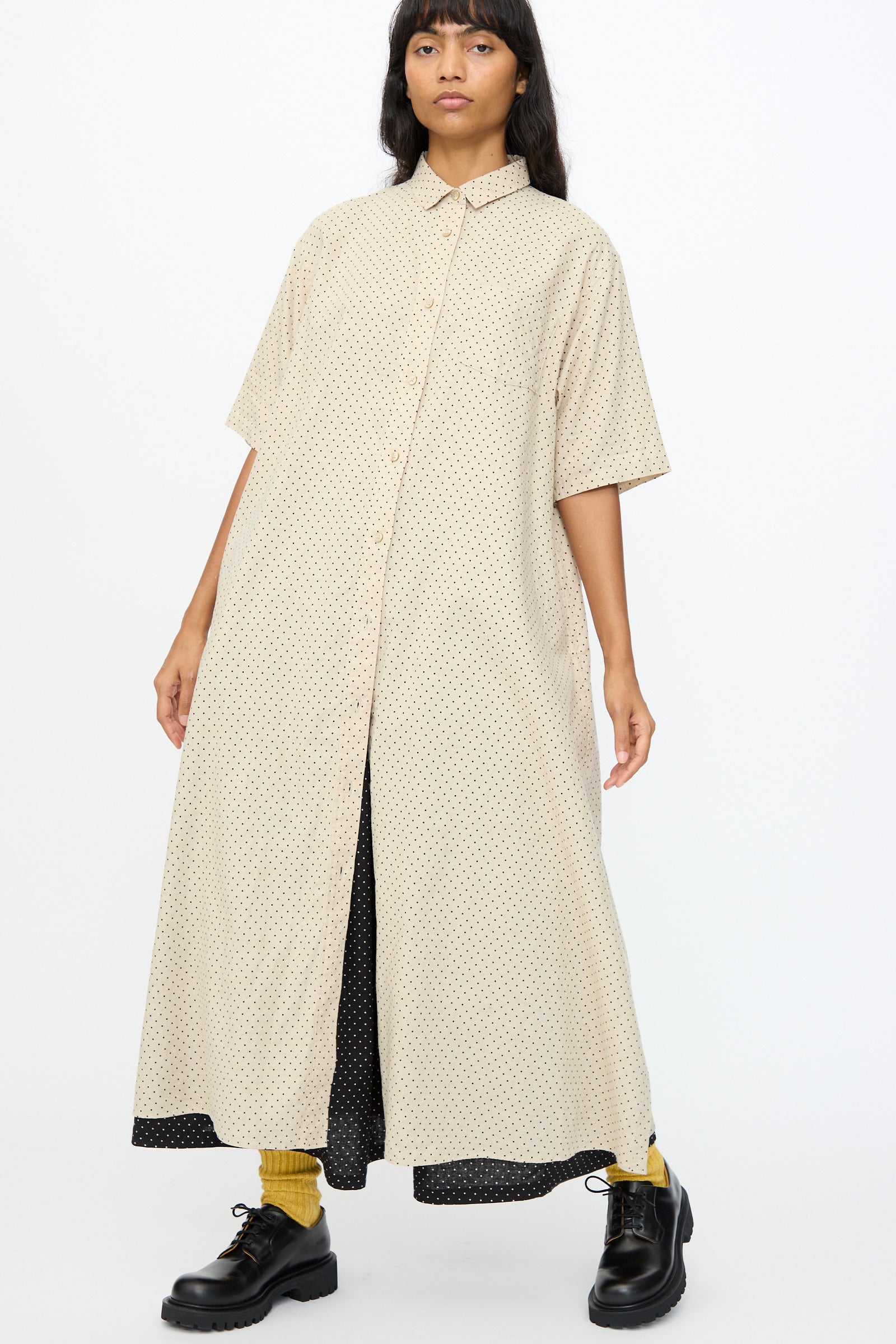 A person wearing the Ichi Antiquités Cotton Linen Dot Dress in Natural stands against a plain white background, paired with yellow socks and black shoes.