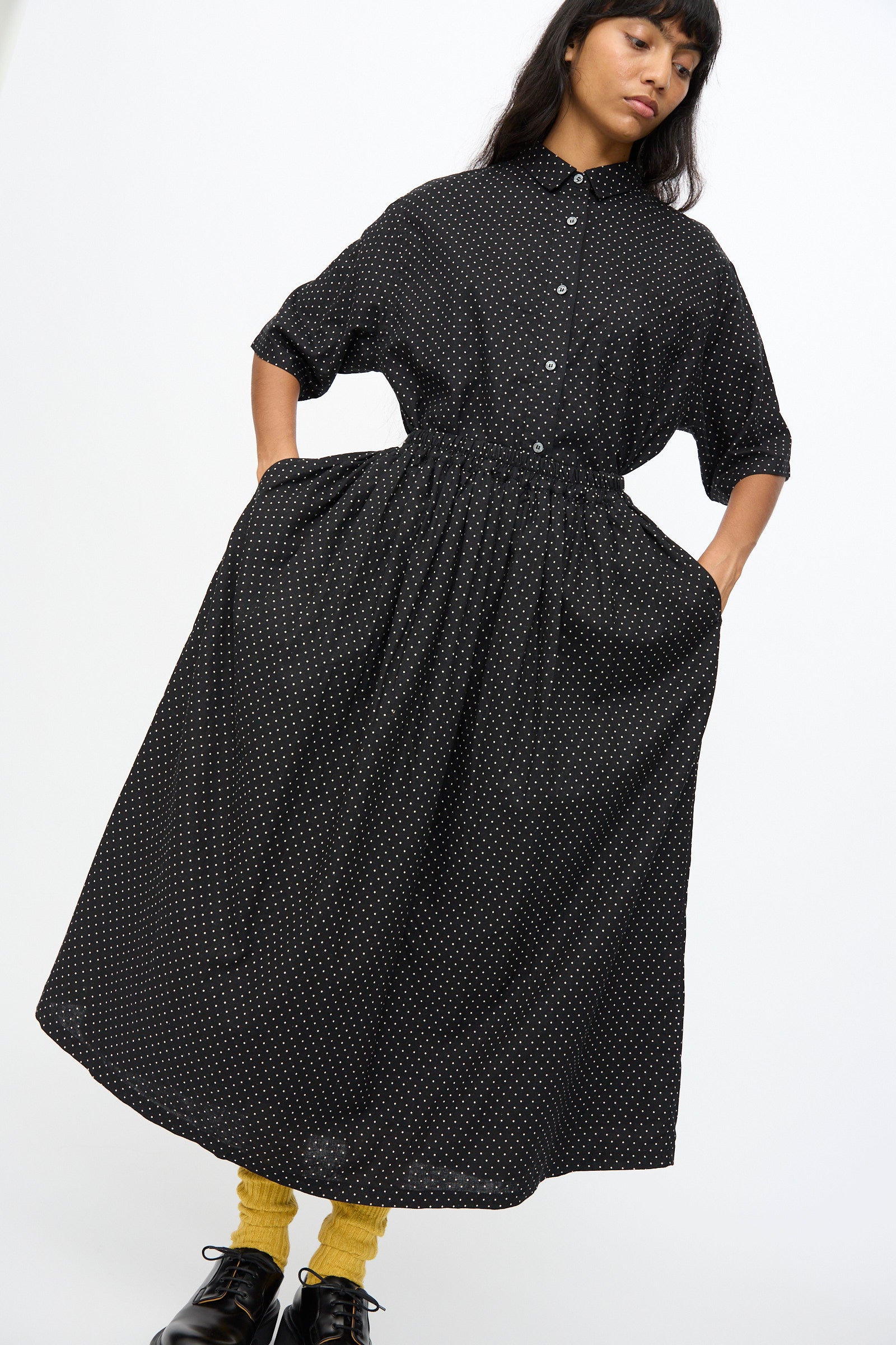 A person wears the Ichi Antiquités Cotton Linen Dot Skirt in Black, styled with yellow socks and black shoes, against a plain background.