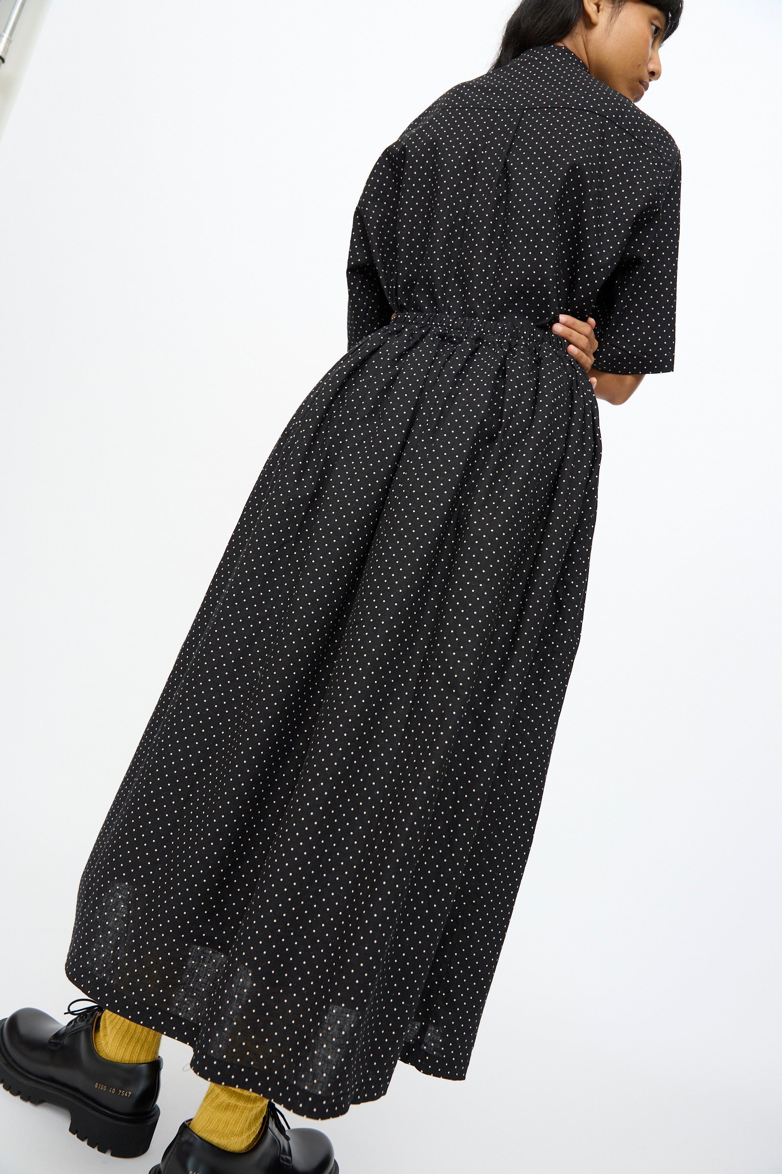 Model wears the Ichi Antiquités Cotton Linen Dot Skirt in Black styled as an ankle-length dress with short sleeves, paired with black platform shoes and yellow socks, standing against a plain white background.