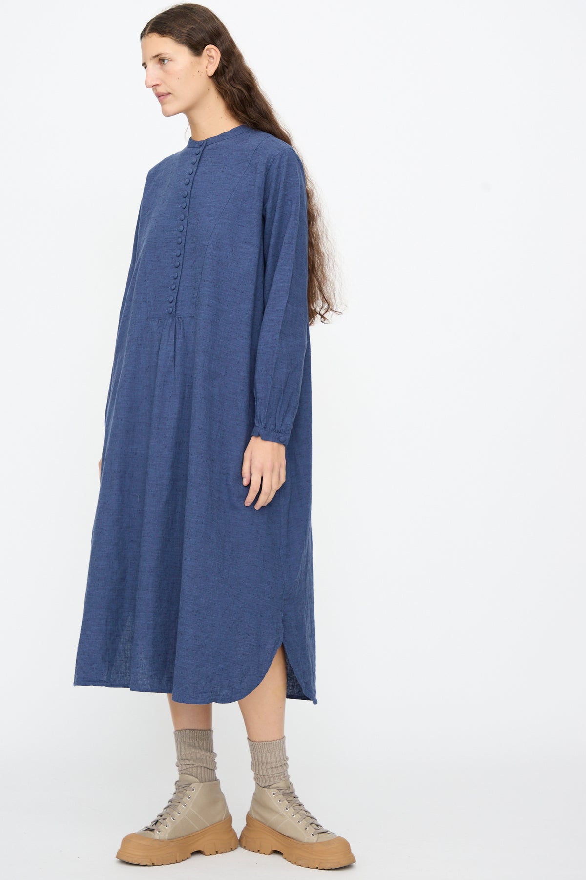 Ichi Antiquités Cotton Linen Nep Dress in Navy, a navy blue long sleeve midi dress with a button-up front and a rounded hem, worn with tan lace-up boots and grey socks.