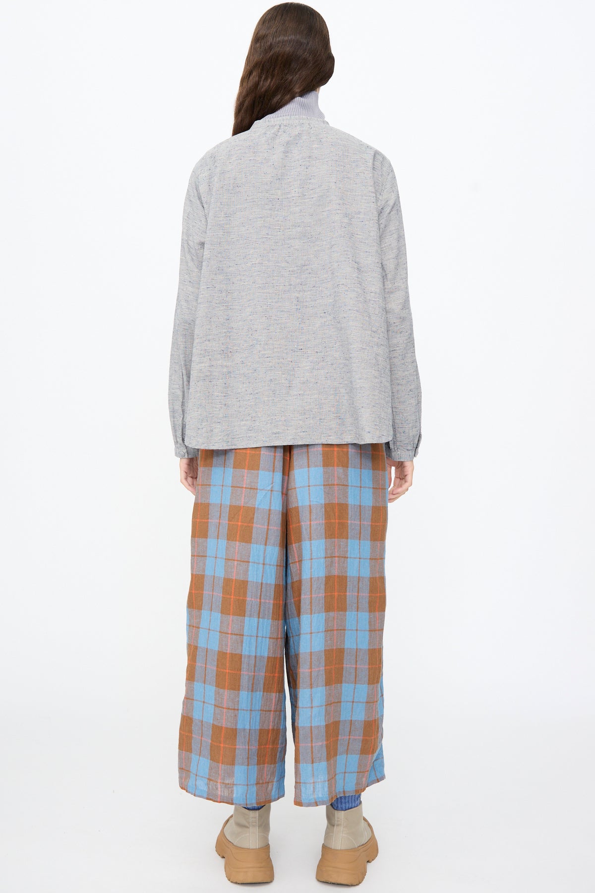 A person seen from the back wearing an Ichi Antiquités Cotton Linen Nep Shirt in Natural, blue and brown plaid wide-leg pants, and tan platform boots.
