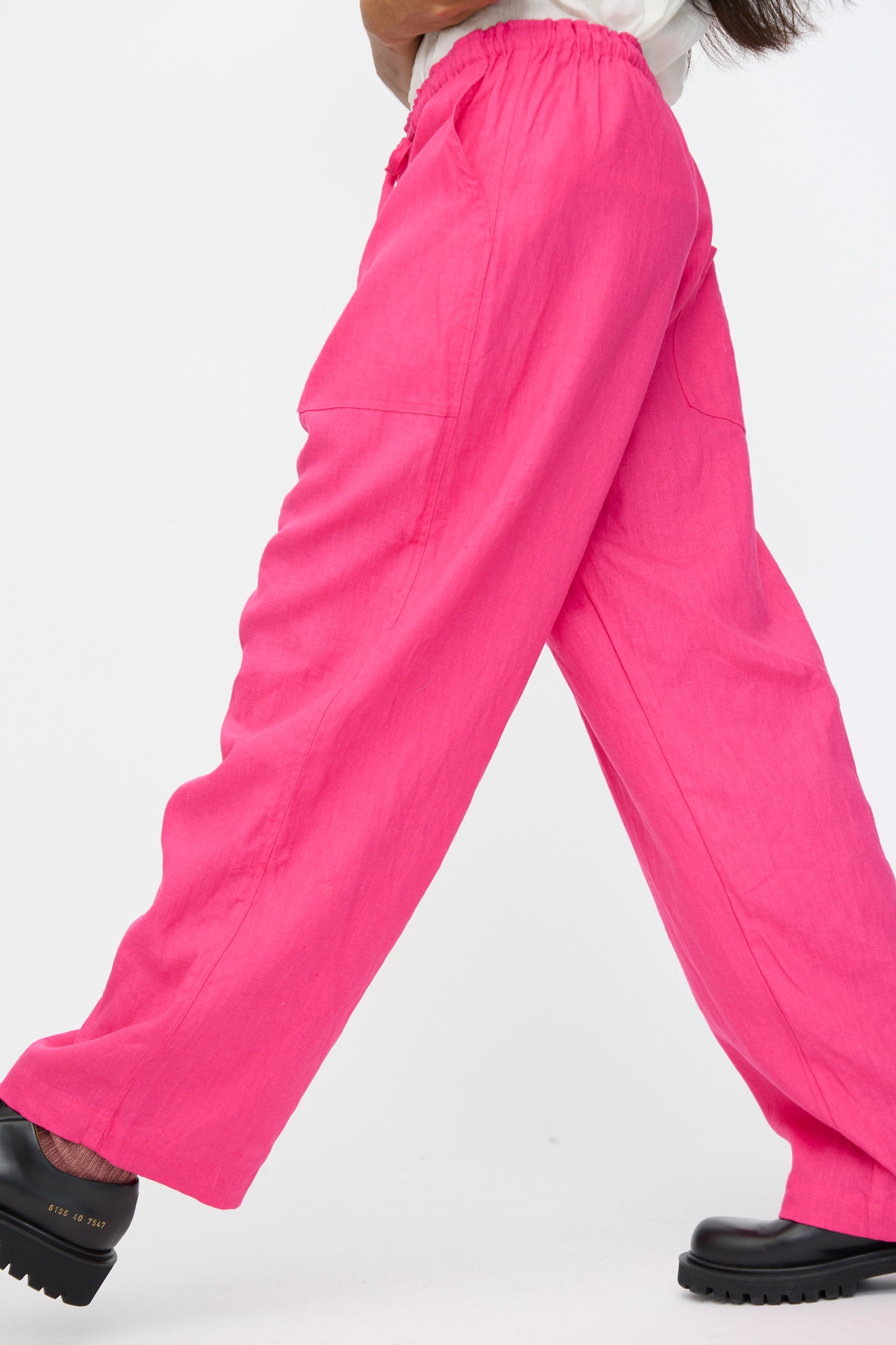 Model wearing Ichi Antiquités Color Linen Pants in Pink, featuring a relaxed fit, paired with black platform shoes, photographed from the side against a plain backdrop.