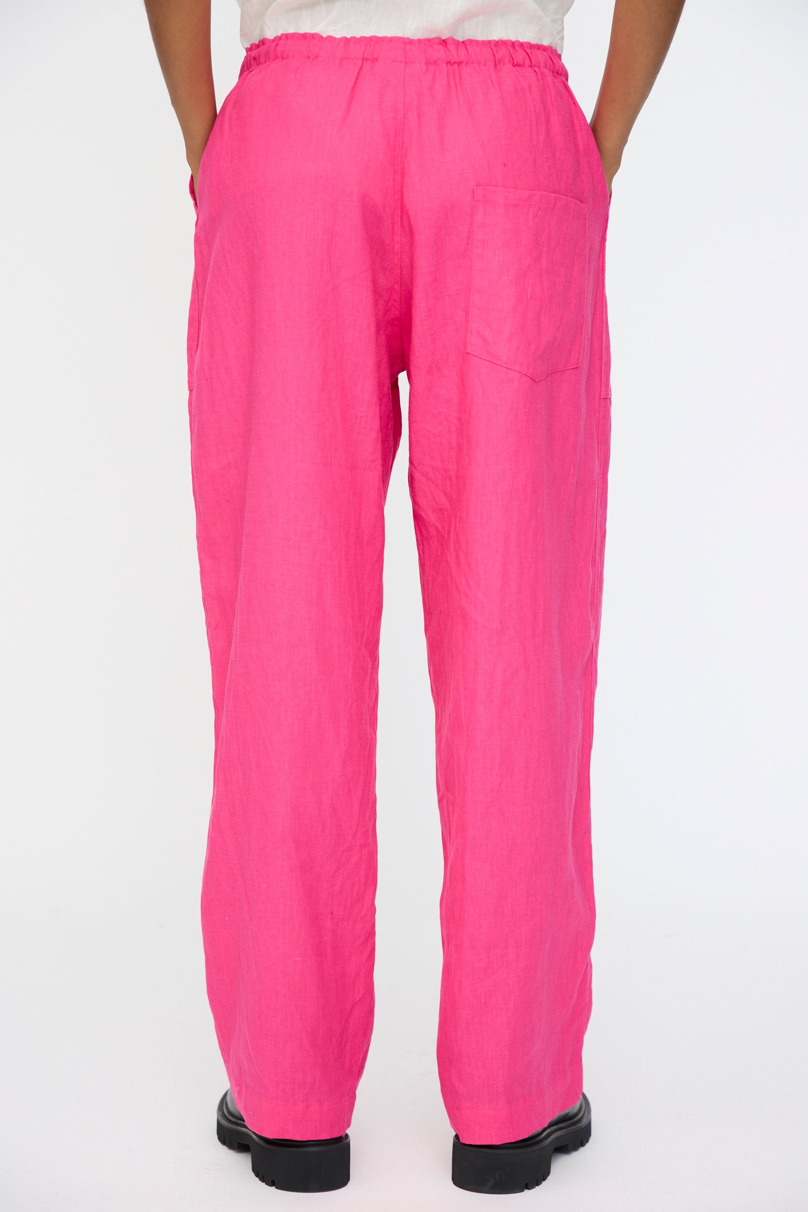 A person wears Ichi Antiquités Color Linen Pants in Pink—relaxed fit, made in Japan with an elastic waistband and single back pocket—standing against a plain white background.