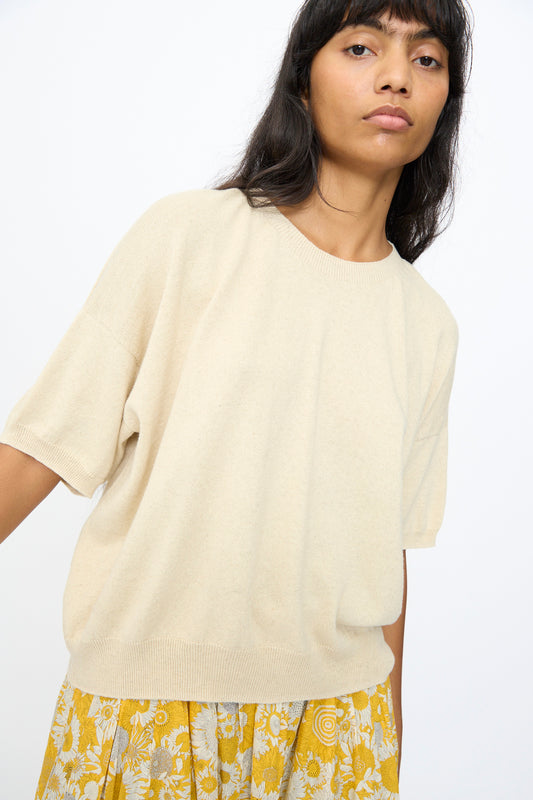 A woman wears the Cotton Linen Pullover in Natural by Ichi Antiquités, paired with a yellow floral skirt, standing against a plain white background.