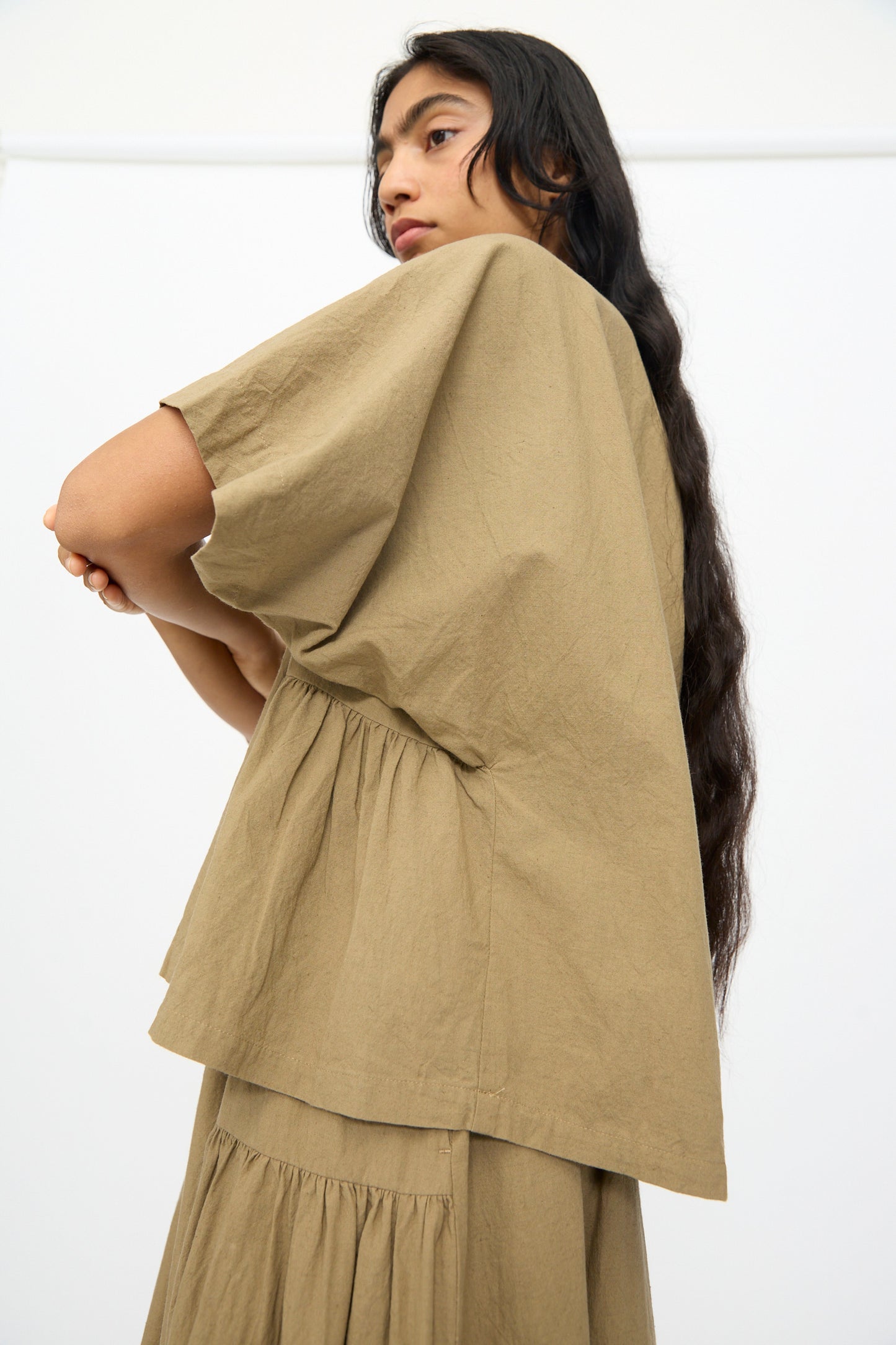 A person with long dark hair, seen in profile against a white background, wears the Ichi Antiquités Cotton Linen Shirt in Mocha.
