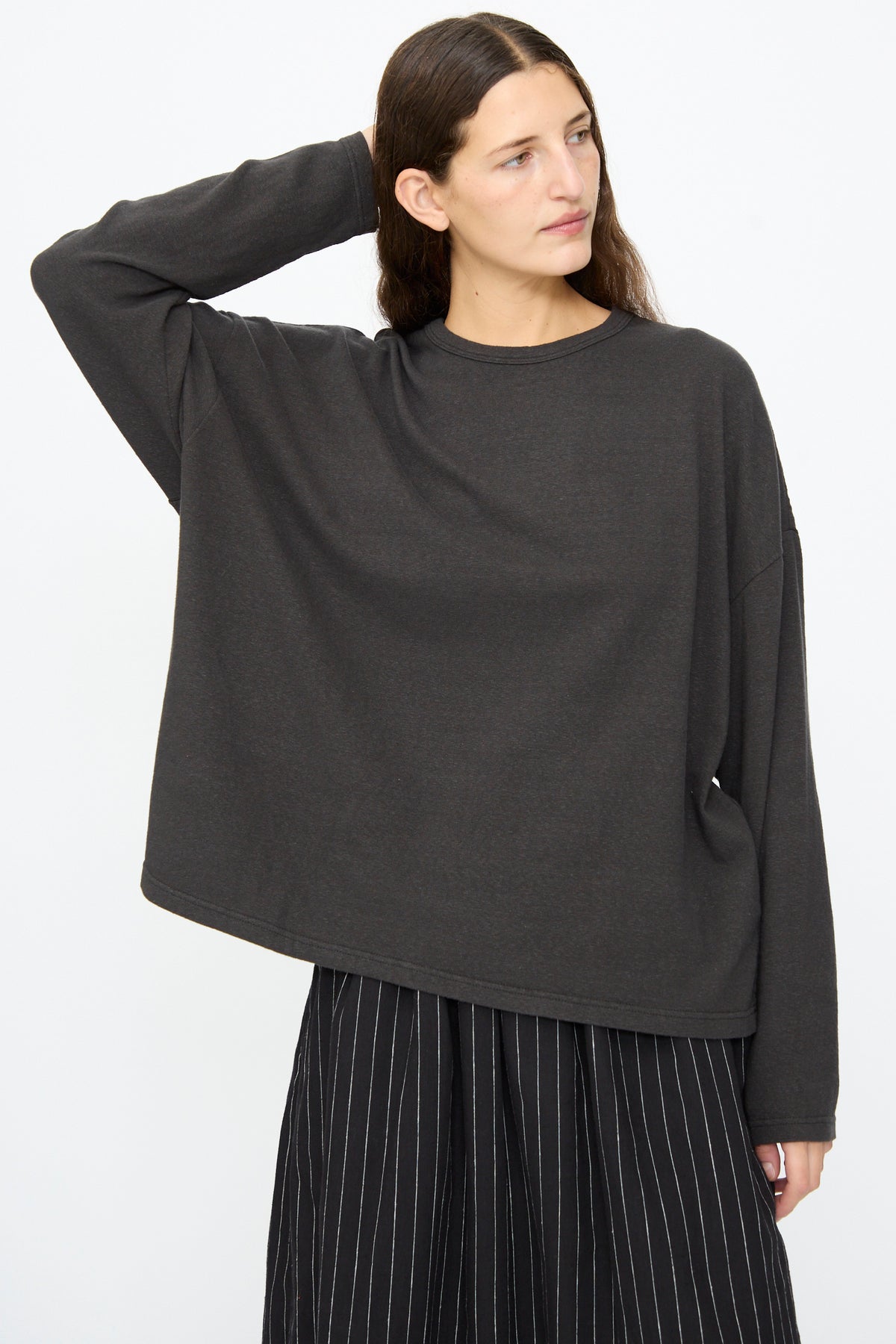 A person wearing a black Ichi Antiquités Cotton Loose Pullover with dropped shoulders and a dark skirt with white pinstripes.