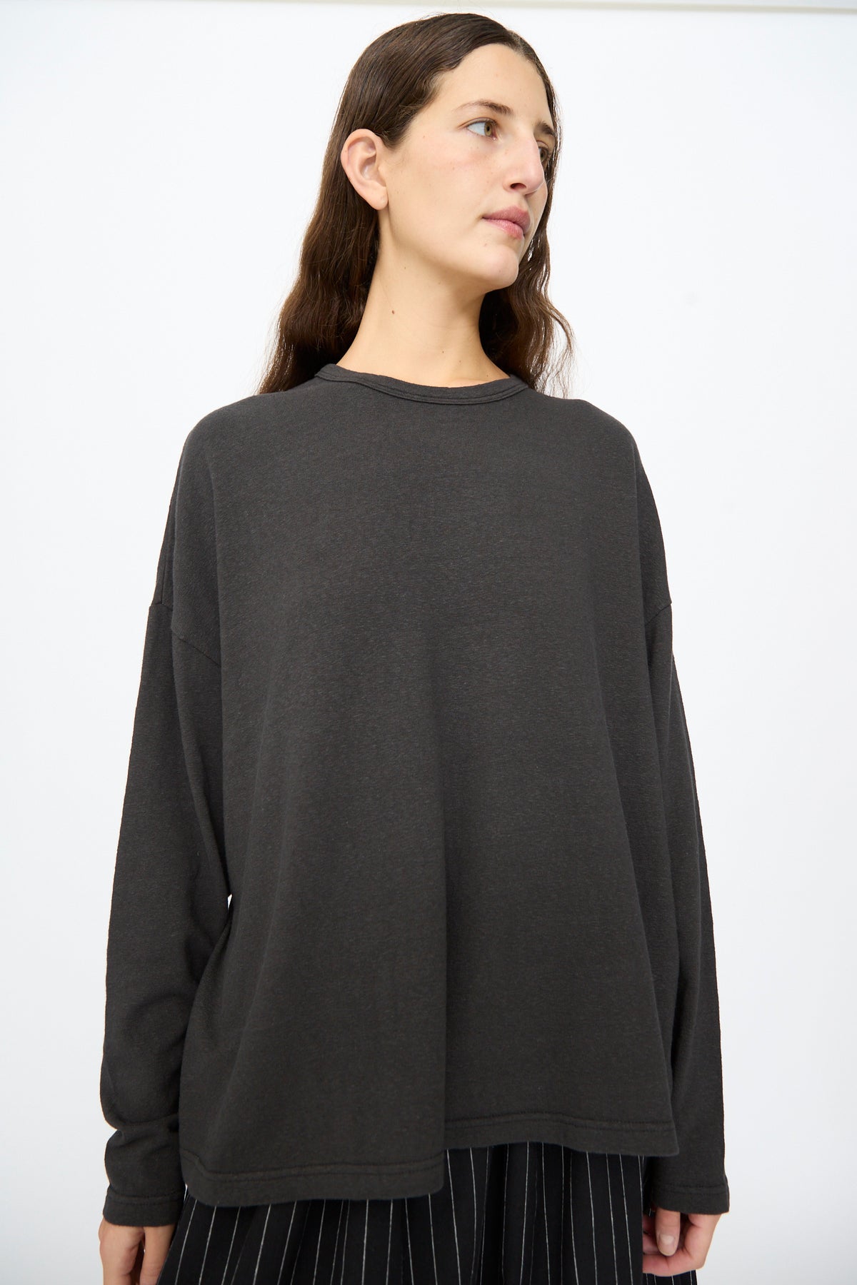 A person wears an Ichi Antiquités Cotton Loose Pullover in Black, a long-sleeved, loose-fitting cotton top with a crew neckline.