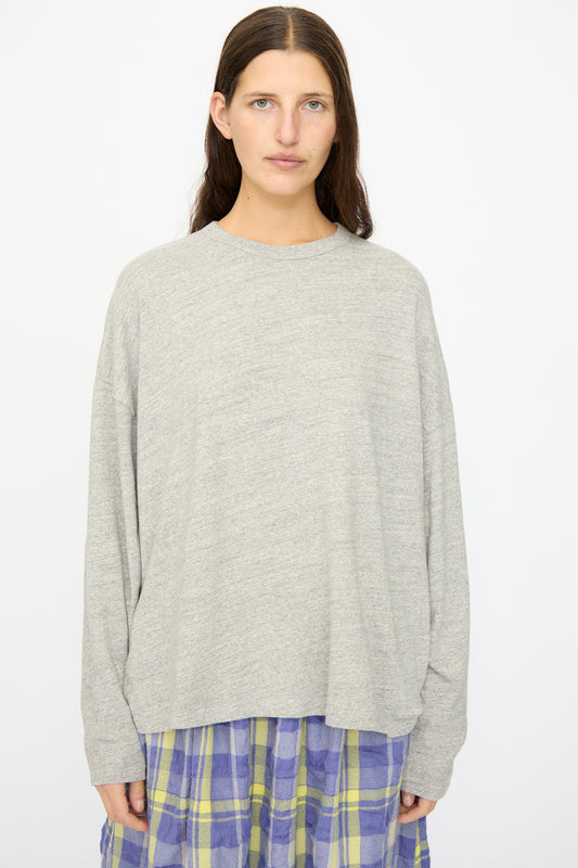 A person with long brown hair wears the Ichi Antiquités Cotton Loose Pullover in Gray, styled with a purple and yellow plaid skirt, standing against a plain white background. The top is crafted in Japan.