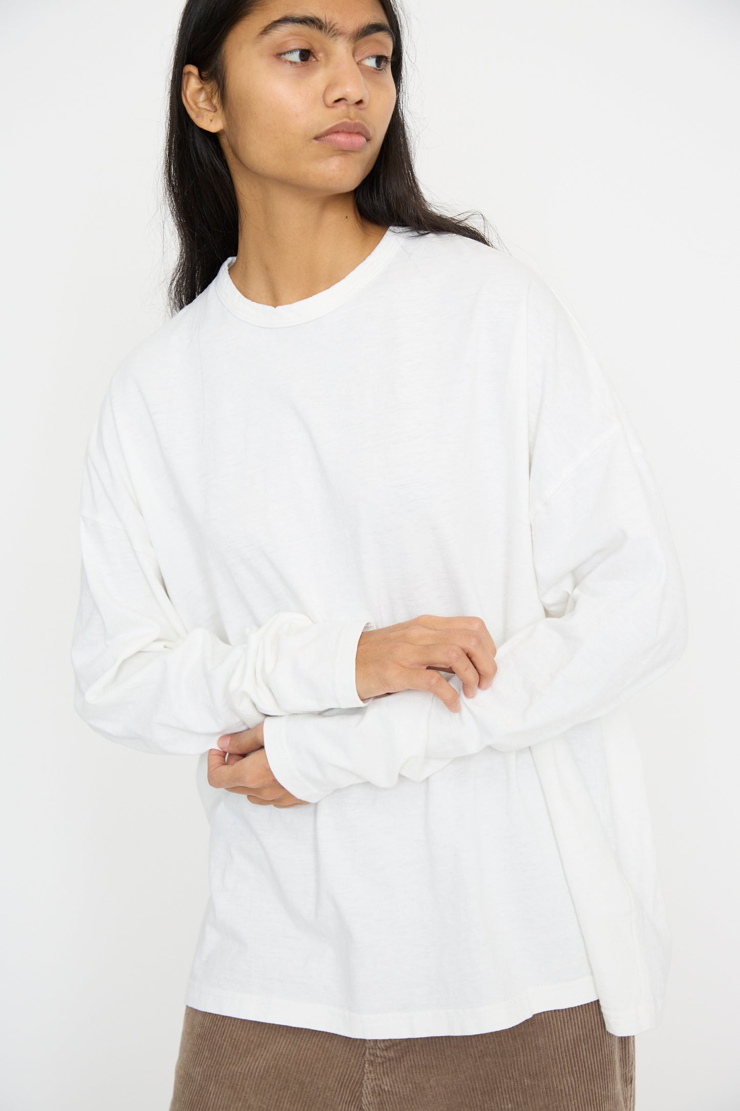 A person wearing an Ichi Antiquités Cotton Loose Pullover in white with brown pants stands against a plain background.