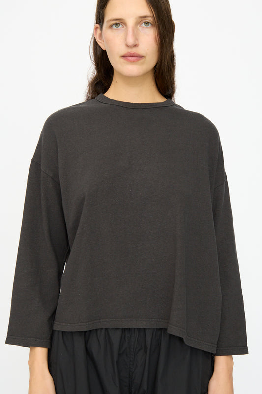 A woman with long brown hair models the Ichi Antiquités Cotton Pullover in Black with a relaxed fit and black pants, standing against a plain white background.