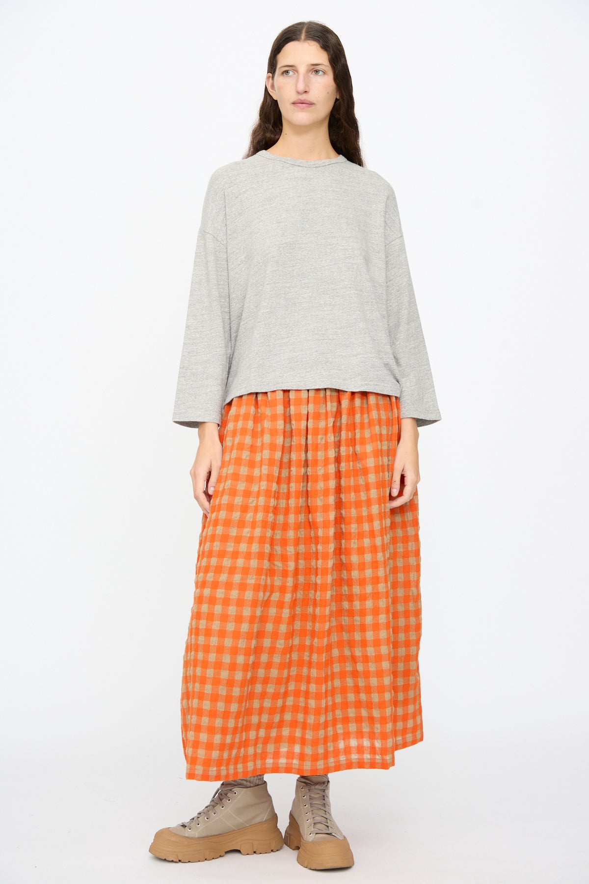 A person wears a relaxed gray Ichi Antiquités Cotton Pullover in Gray, a long orange gingham skirt, and beige lace-up boots.