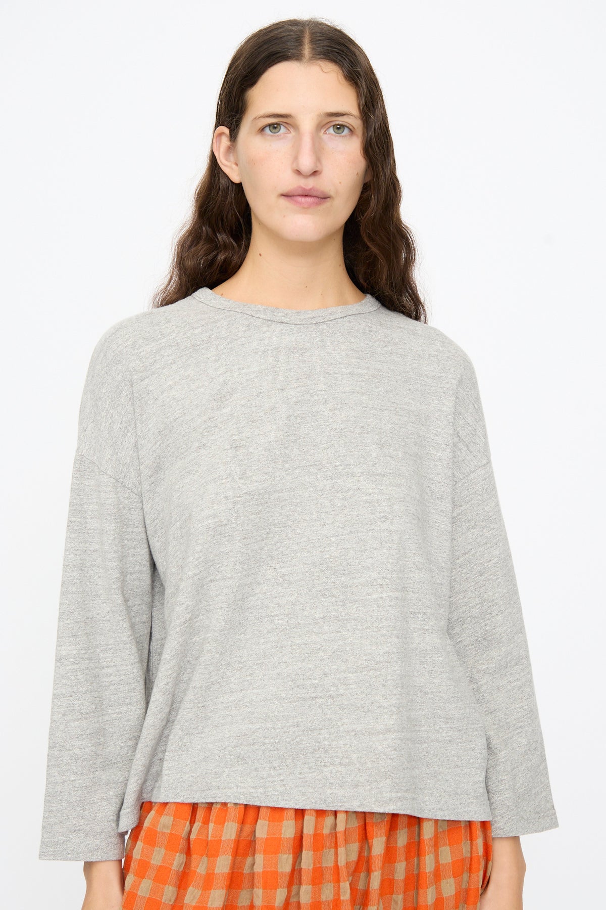 A person wearing a gray Cotton Pullover in Gray over an orange and white checkered skirt.
