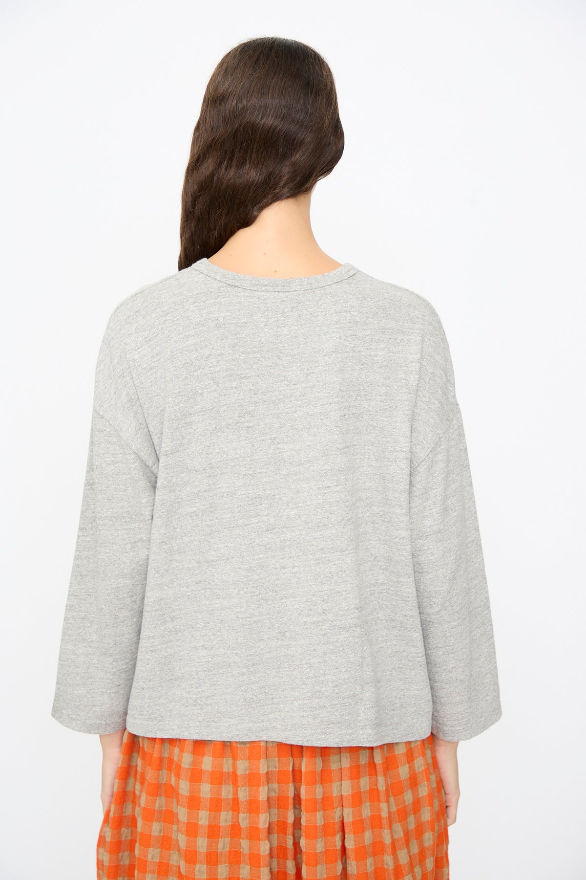 Back view of a person wearing a relaxed, long-sleeved gray Ichi Antiquités Cotton Pullover over an orange and beige checkered skirt.