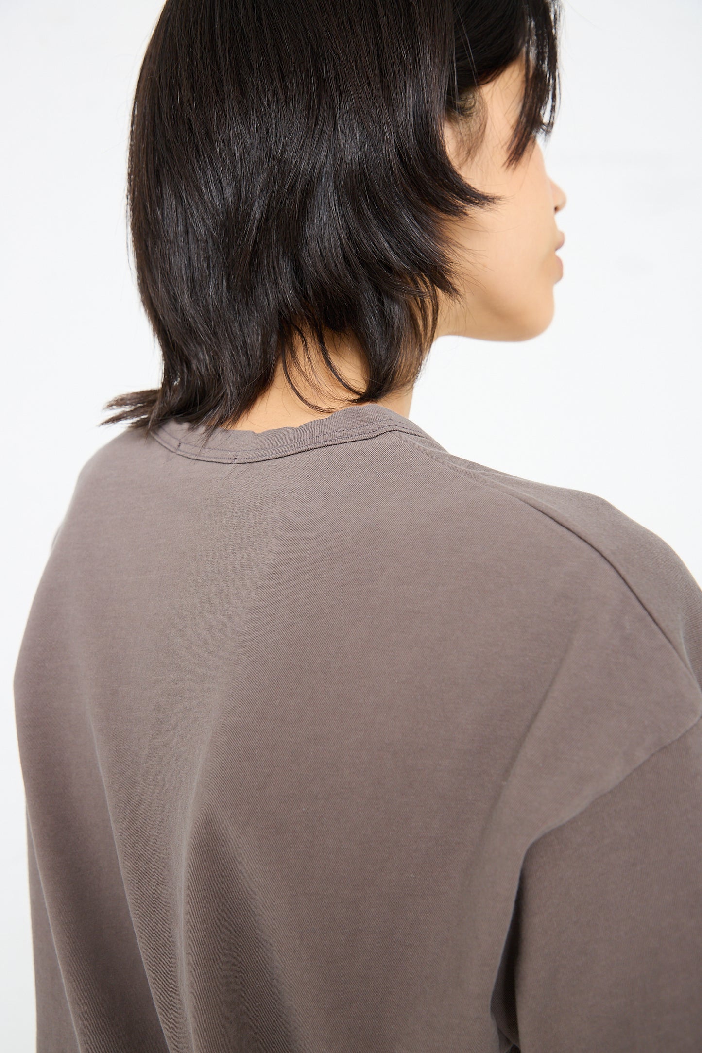 A person with short, dark hair wearing a gray **Cotton Pullover Tee in Mocha** by **Ichi Antiquités**, photographed from behind.