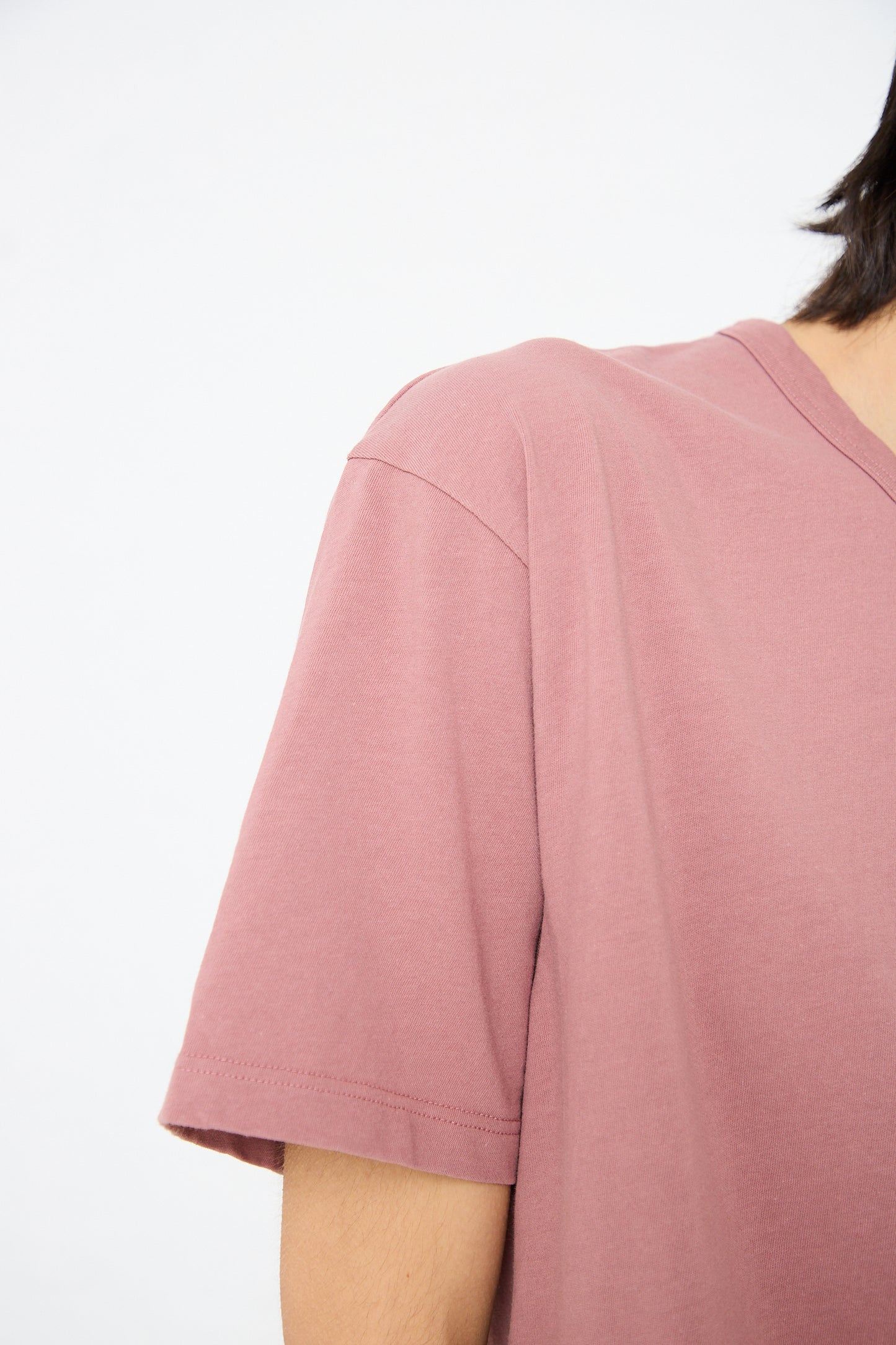 A close-up of a person wearing an Ichi Antiquités Cotton Pullover Tee in Pink, with only the shoulder and partial arm visible against a white background.