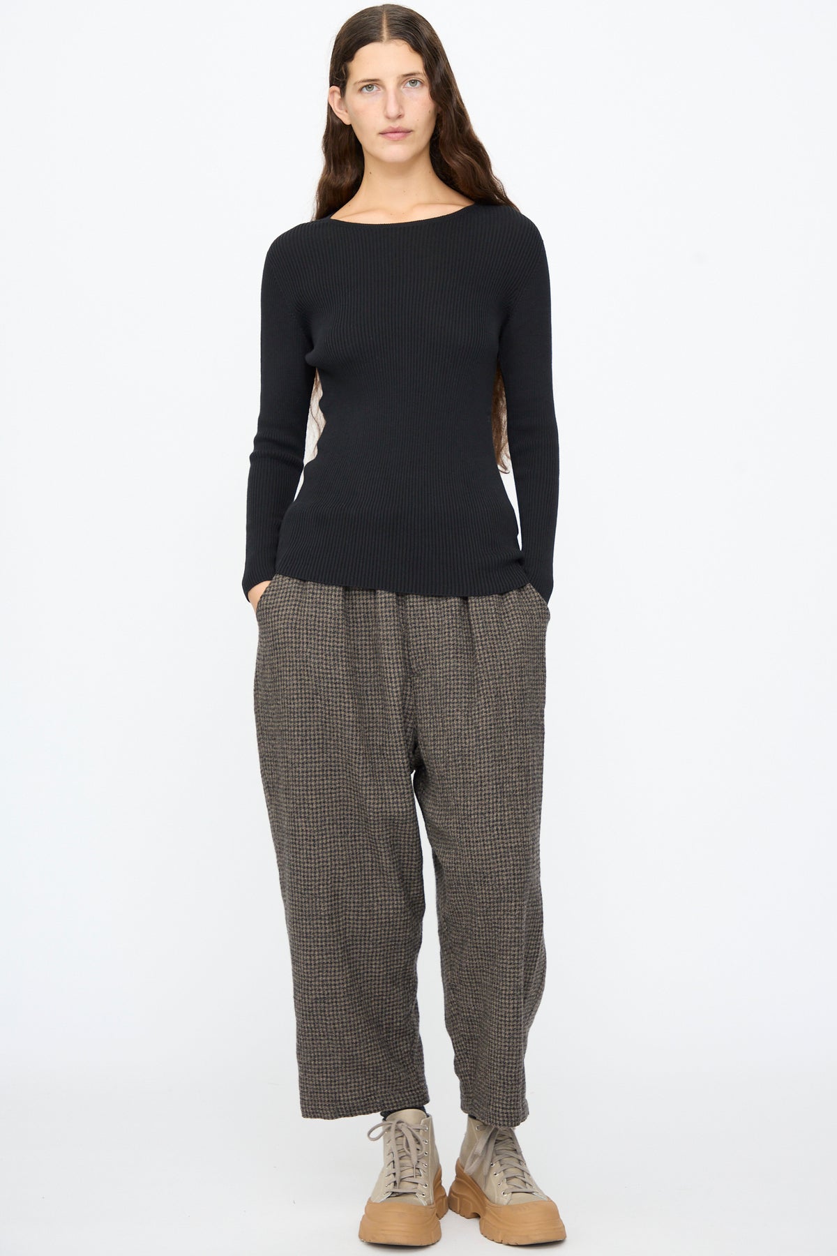 A person wears an Ichi Antiquités Cotton Rib Knit Pullover in black, dark patterned wide-leg trousers, and tan lace-up sneakers.