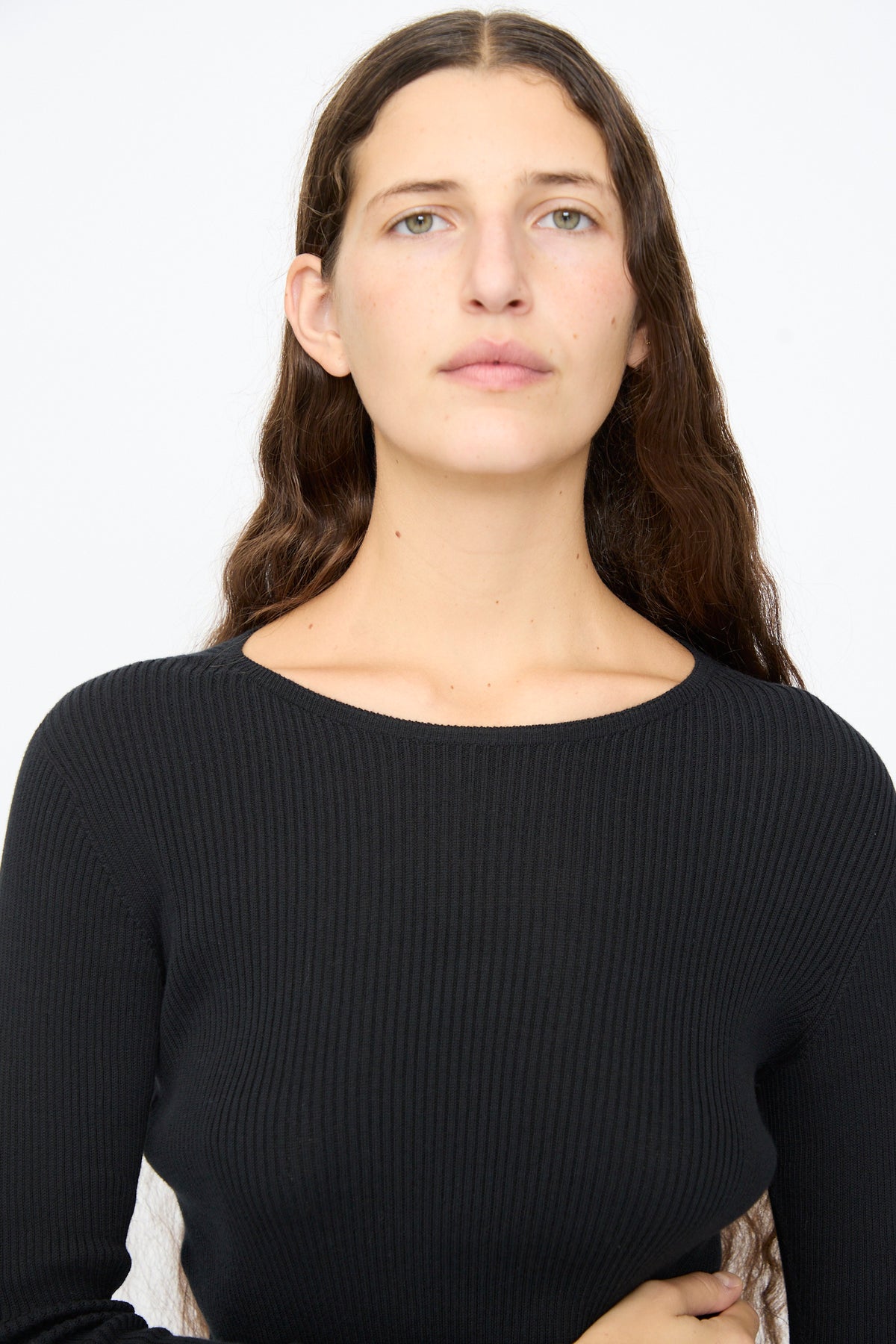 A person wearing an Ichi Antiquités Cotton Rib Knit Pullover in black, featuring a slim-fit, cotton rib knit design with a crew neckline.