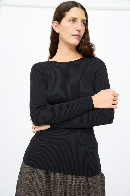 A person wearing a slim fit, black Cotton Rib Knit Pullover by Ichi Antiquités featuring a scop\op neckline, paired with brown patterned trousers