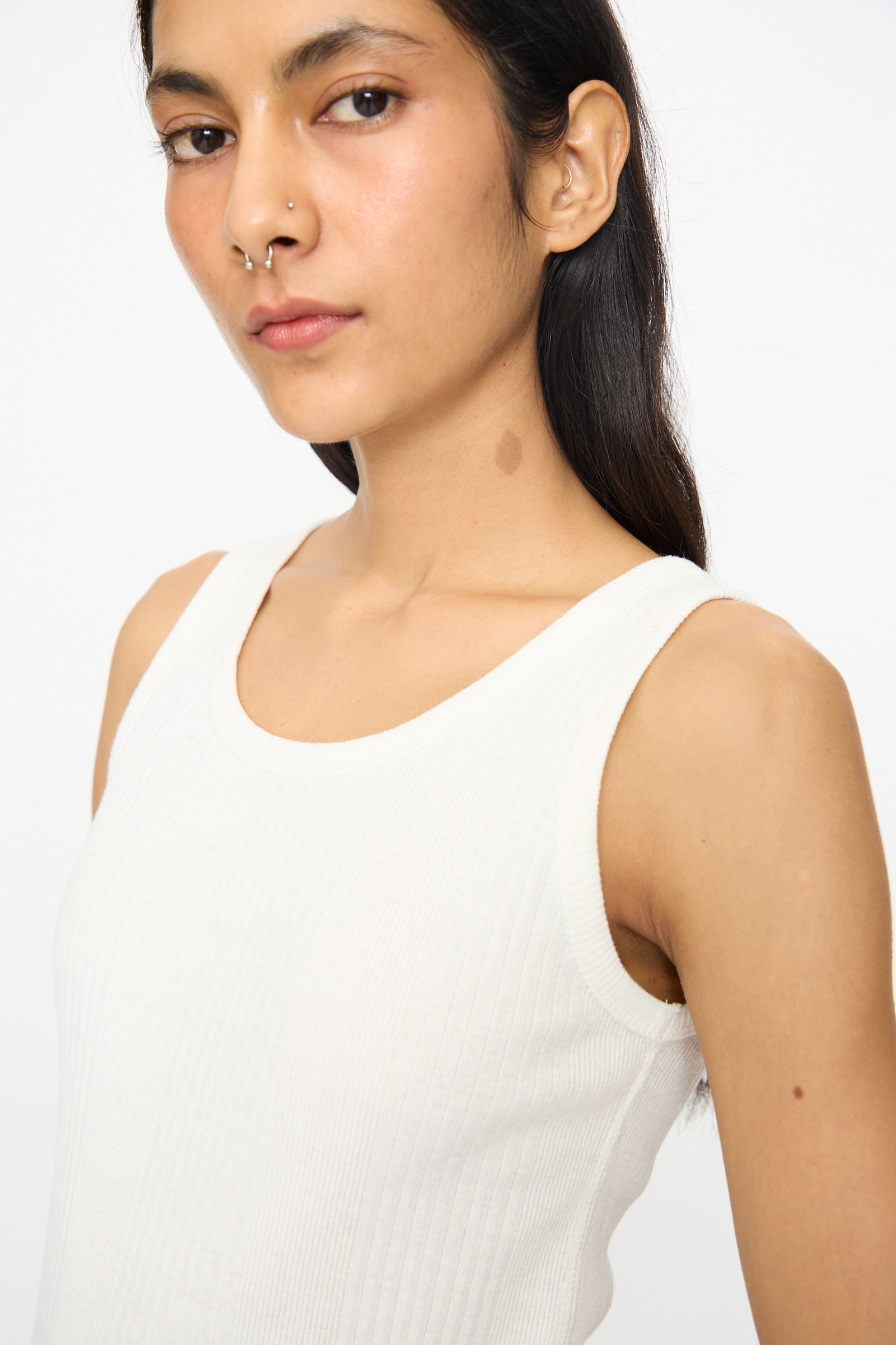 A person with long dark hair wears the Ichi Antiquités Cotton Rib Tank Top in White, featuring a scoop neck, and looks at the camera with a neutral expression.