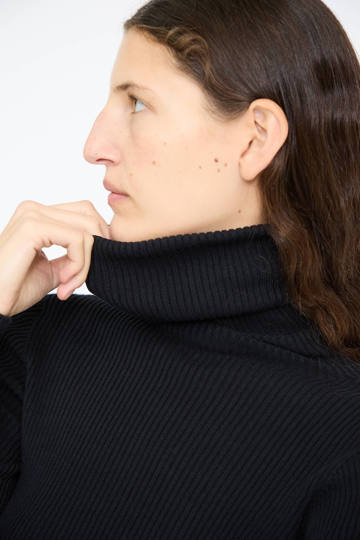 A person with long brown hair wears the Black Cotton Rib Turtleneck by Ichi Antiquités, looking to the side.