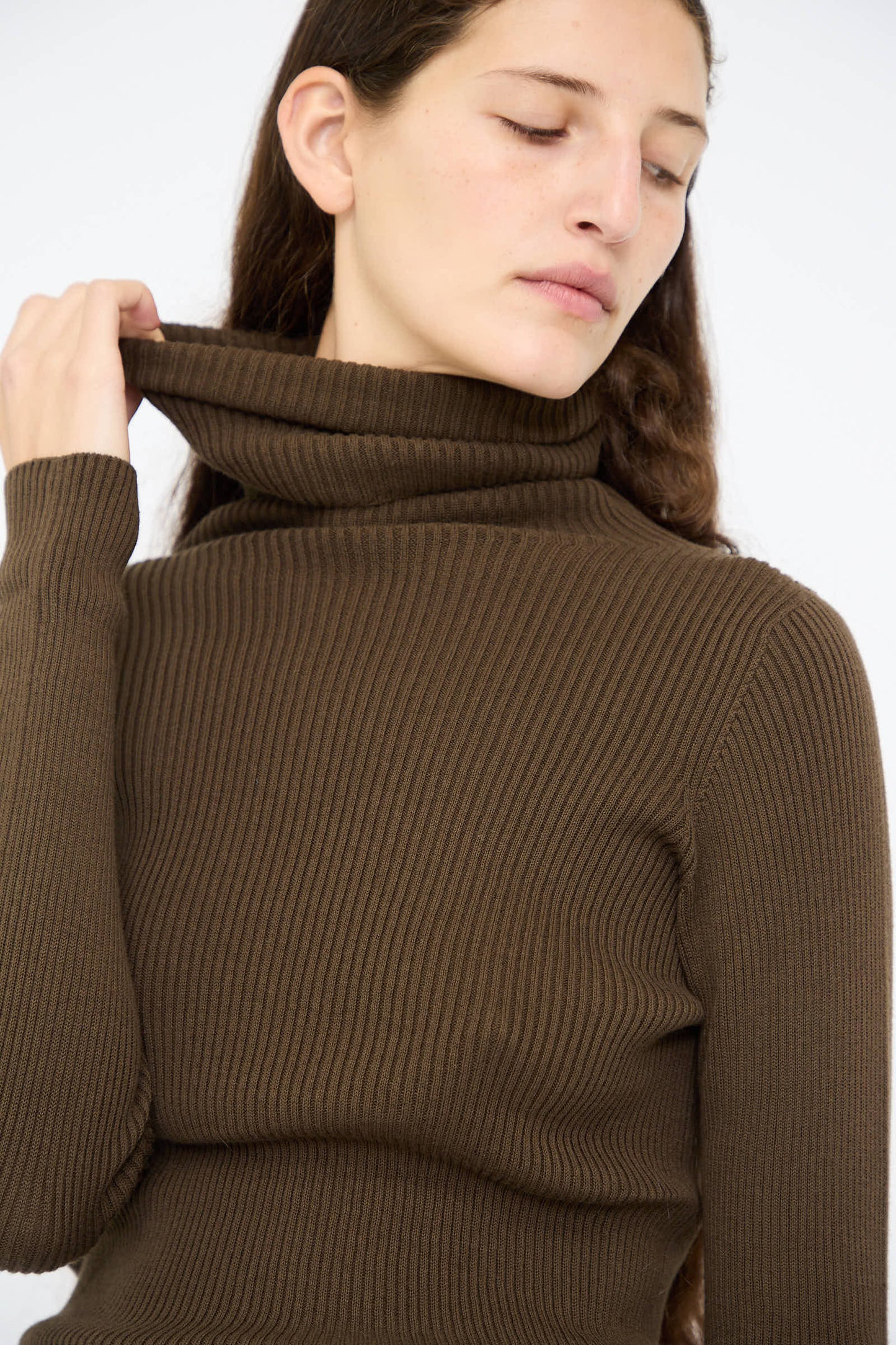 A person wearing the Cotton Rib Turtleneck in Brown by Ichi Antiquités, gazing thoughtfully to the side against a plain background.