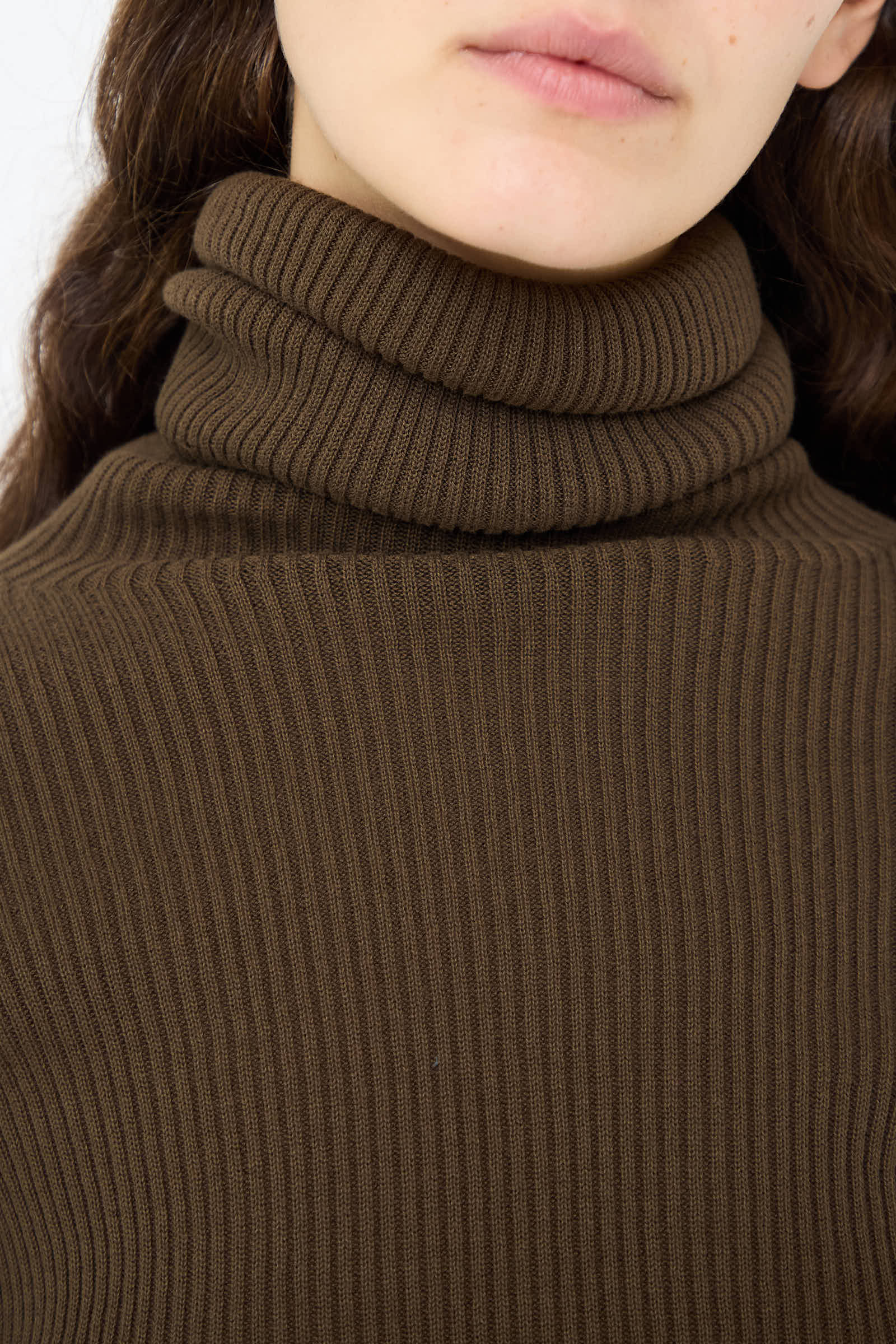 Close-up of a person wearing the Ichi Antiquités Cotton Rib Turtleneck in Brown. The face is partially visible, with emphasis on the texture of the clothing.